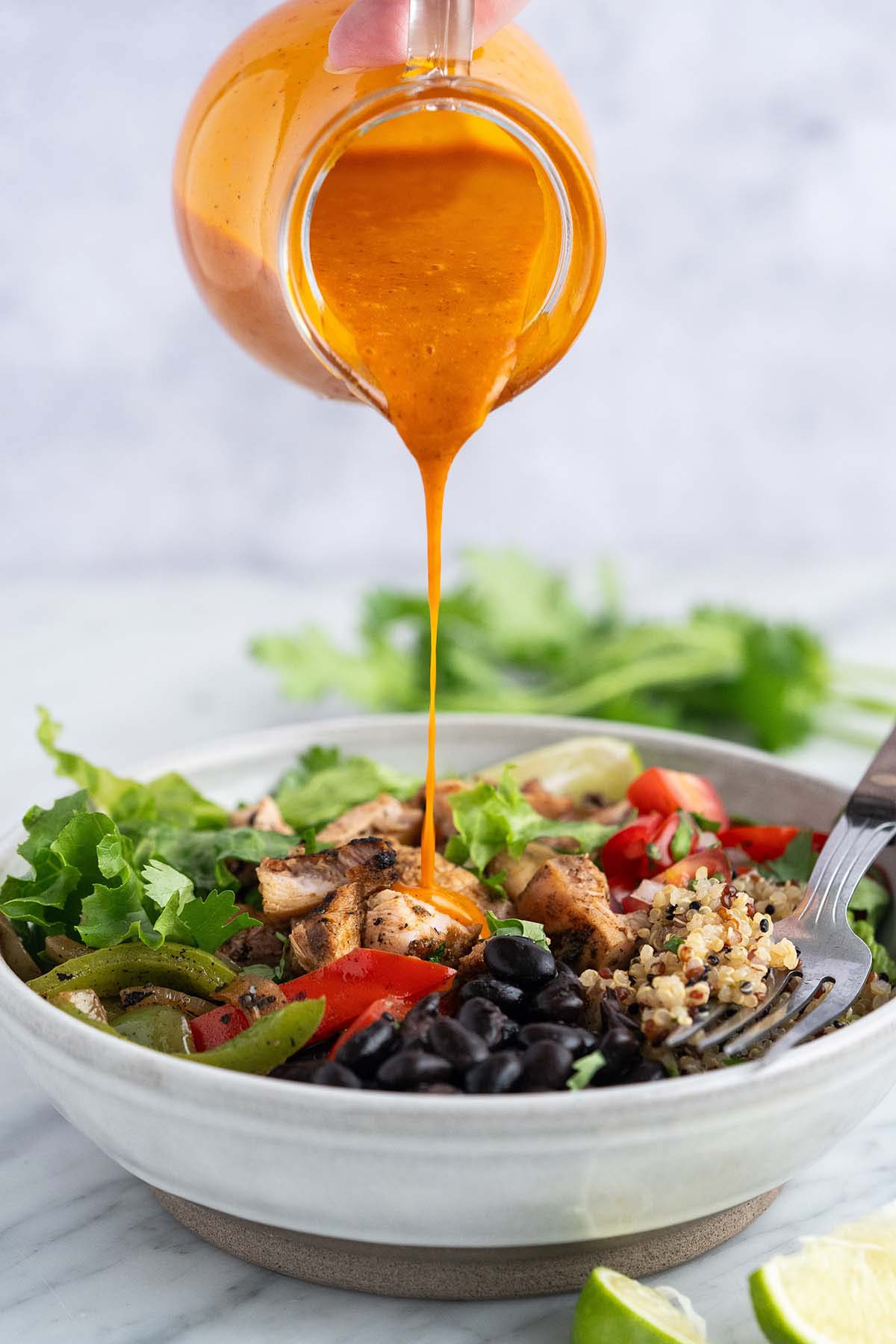 pouring smoky honey adobo dressing onto salad