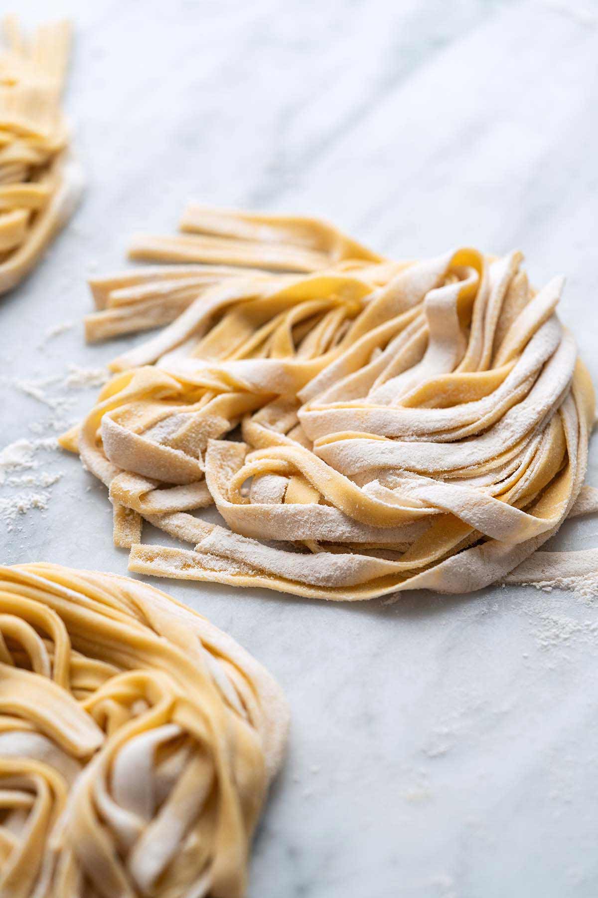 front view of fresh pasta noodles in nest shapes on marble countertop made with sourdough discard