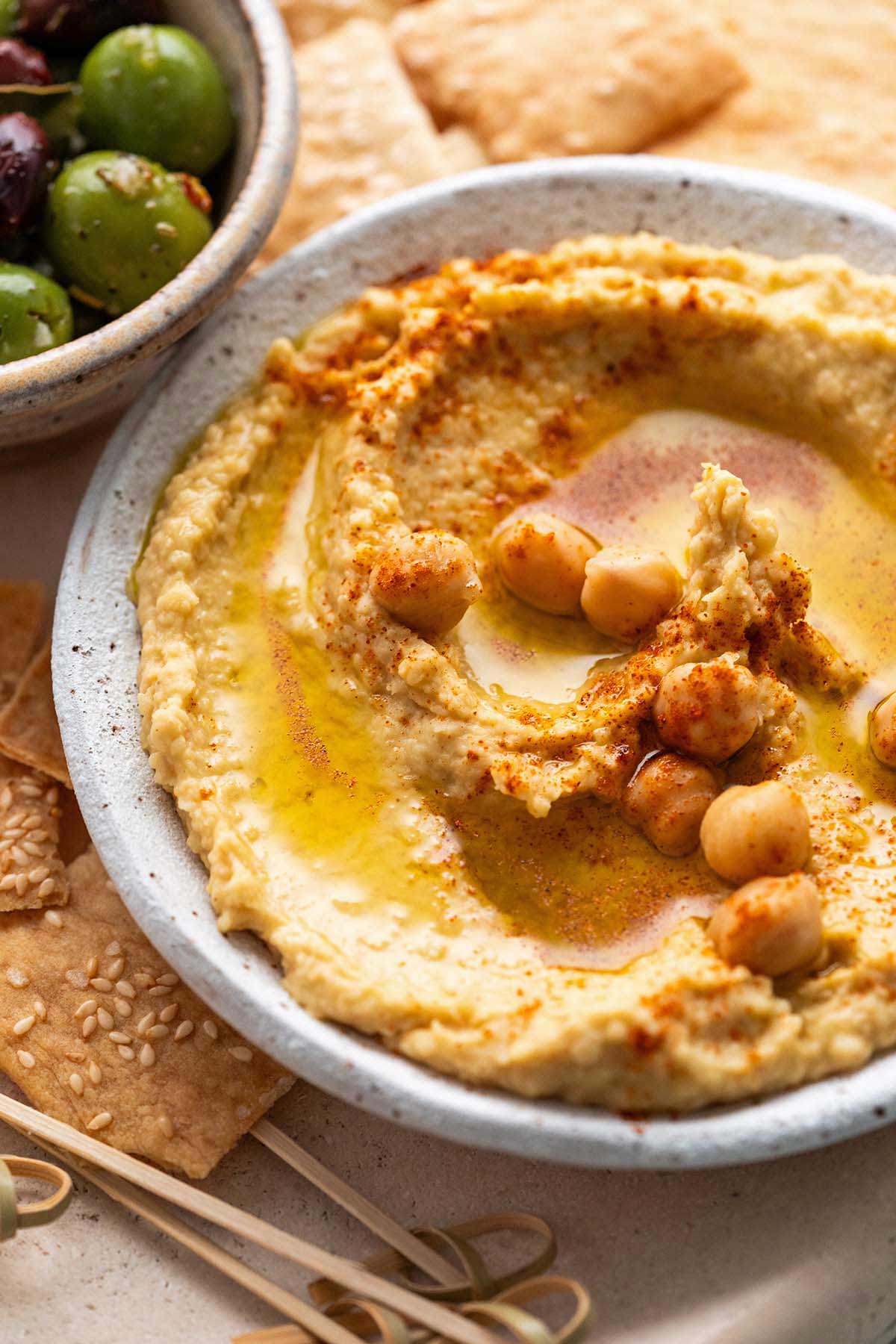 creamy garlic hummus recipe without tahini next to crackers and olives