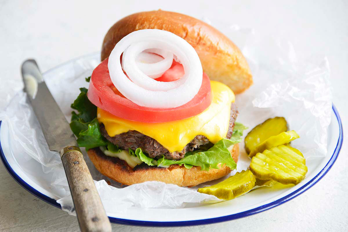 cheeseburger on bun with the works cooked in a cast iron pan