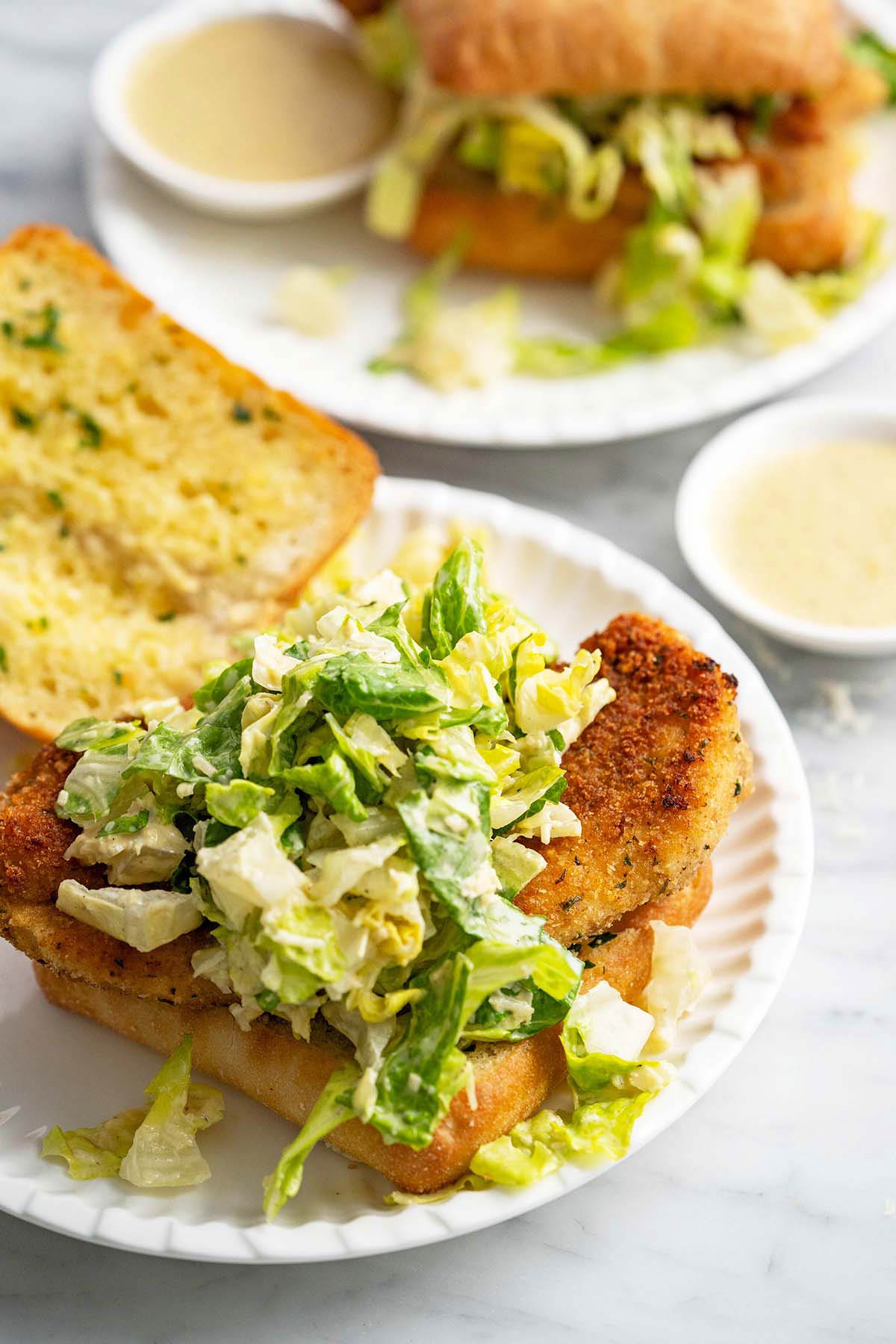chicken cutlets with caesar salad on garlic bread ciabatta rolls