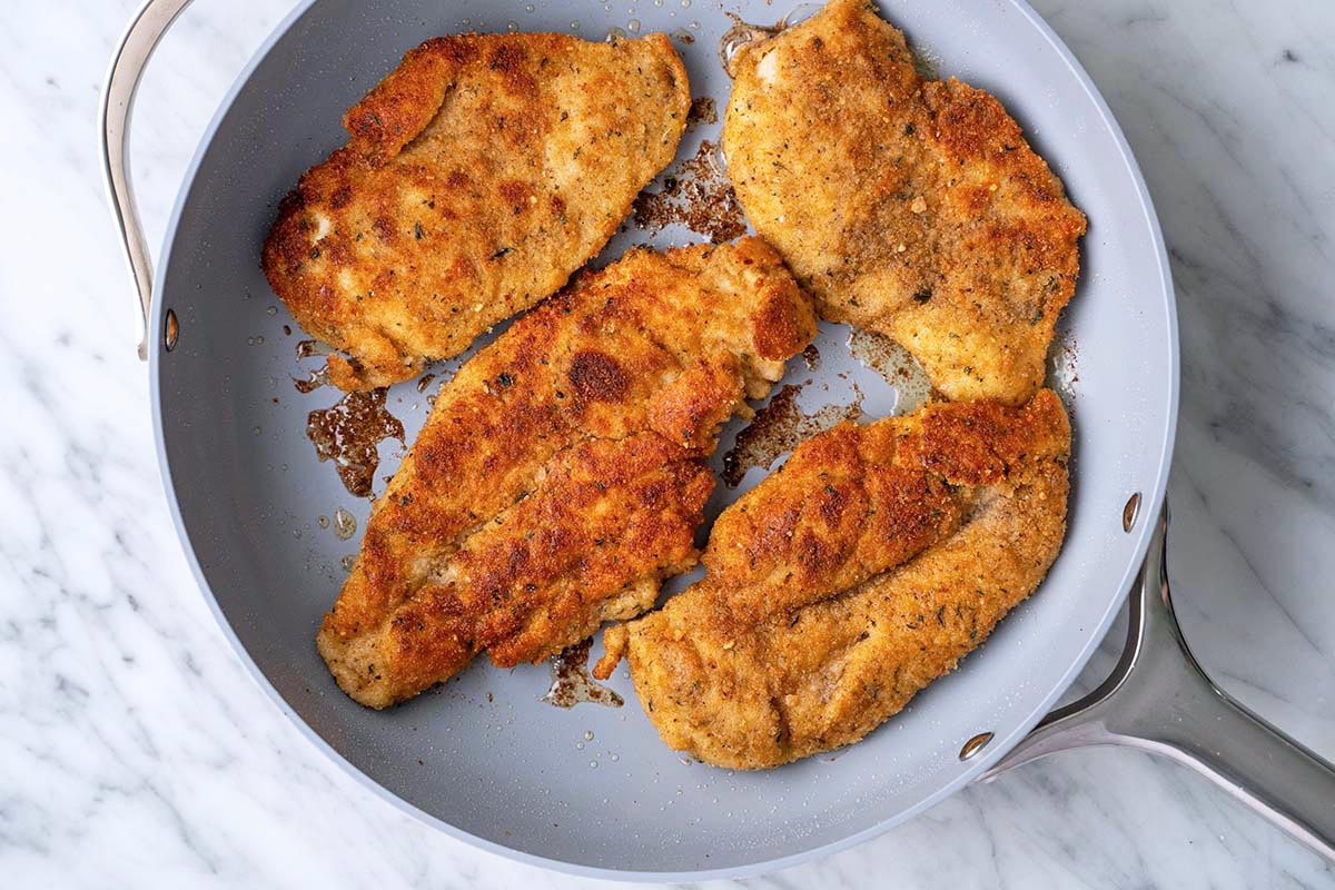 golden breaded chicken cutlets in skillet