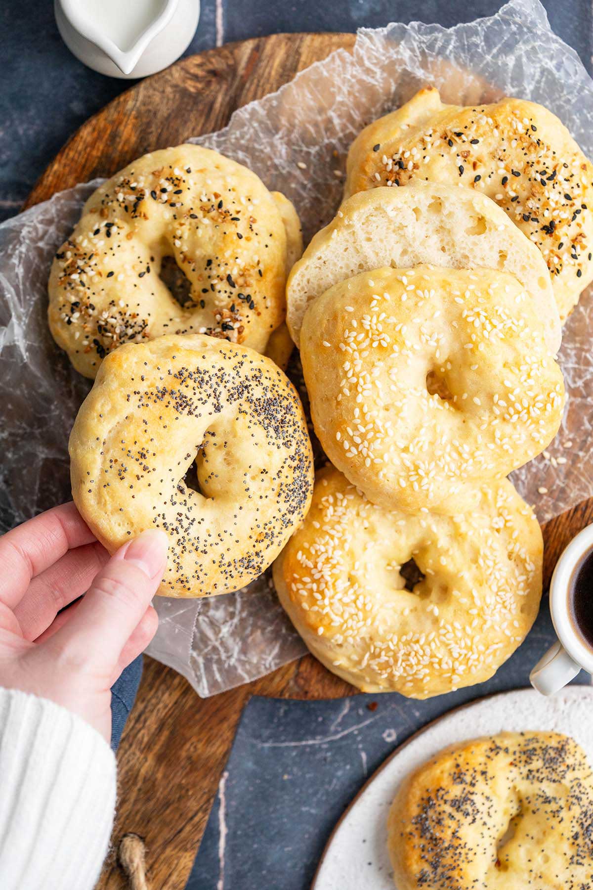 hand reaching in to grab poppy seed protein bagel from platter