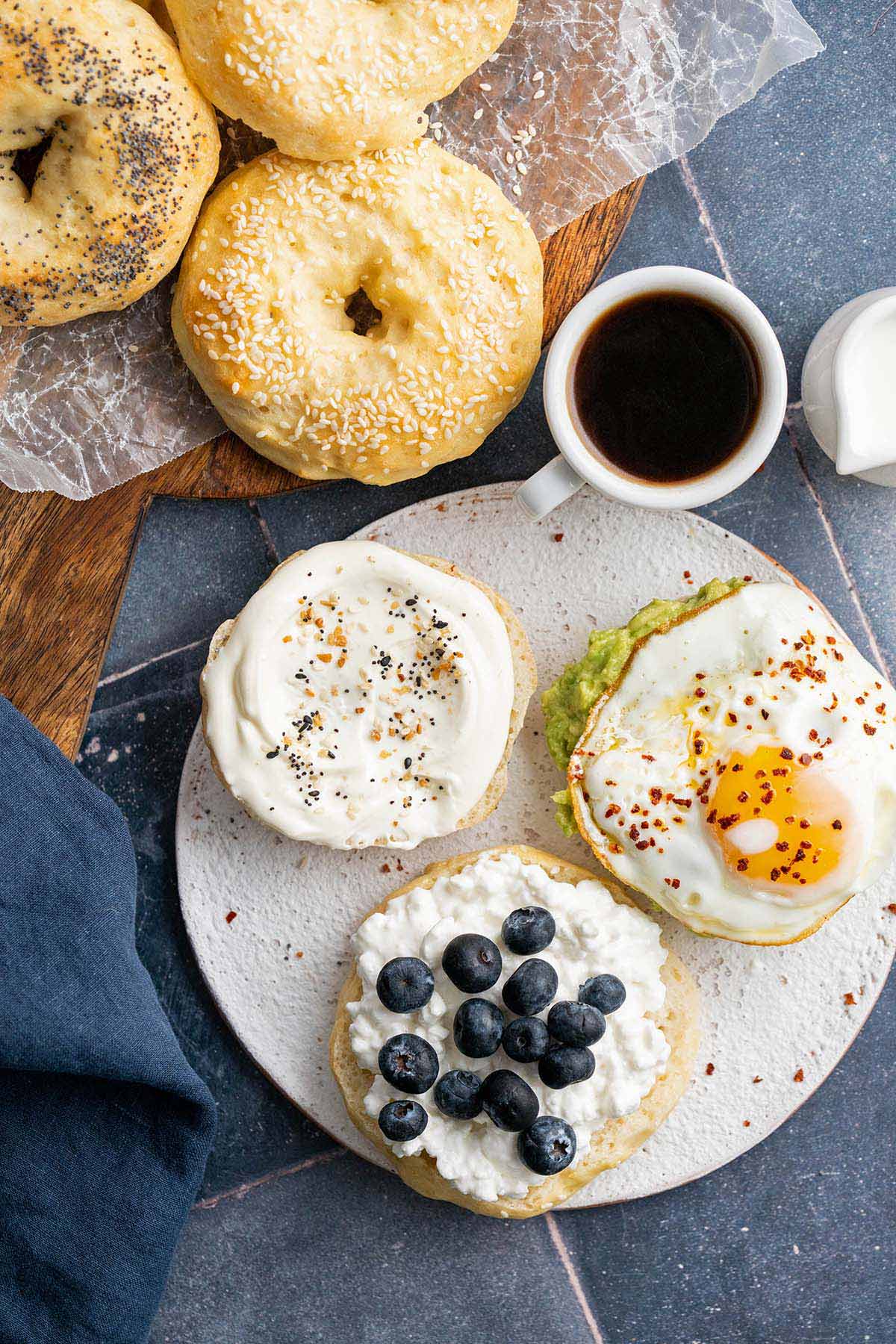 top view of plate of protein bagels with healthy toppings like cottage cheese avocado egg and blueberries