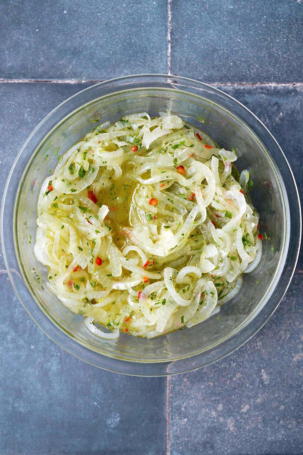 brazilian onion salad in glass bowl on blue tiled table