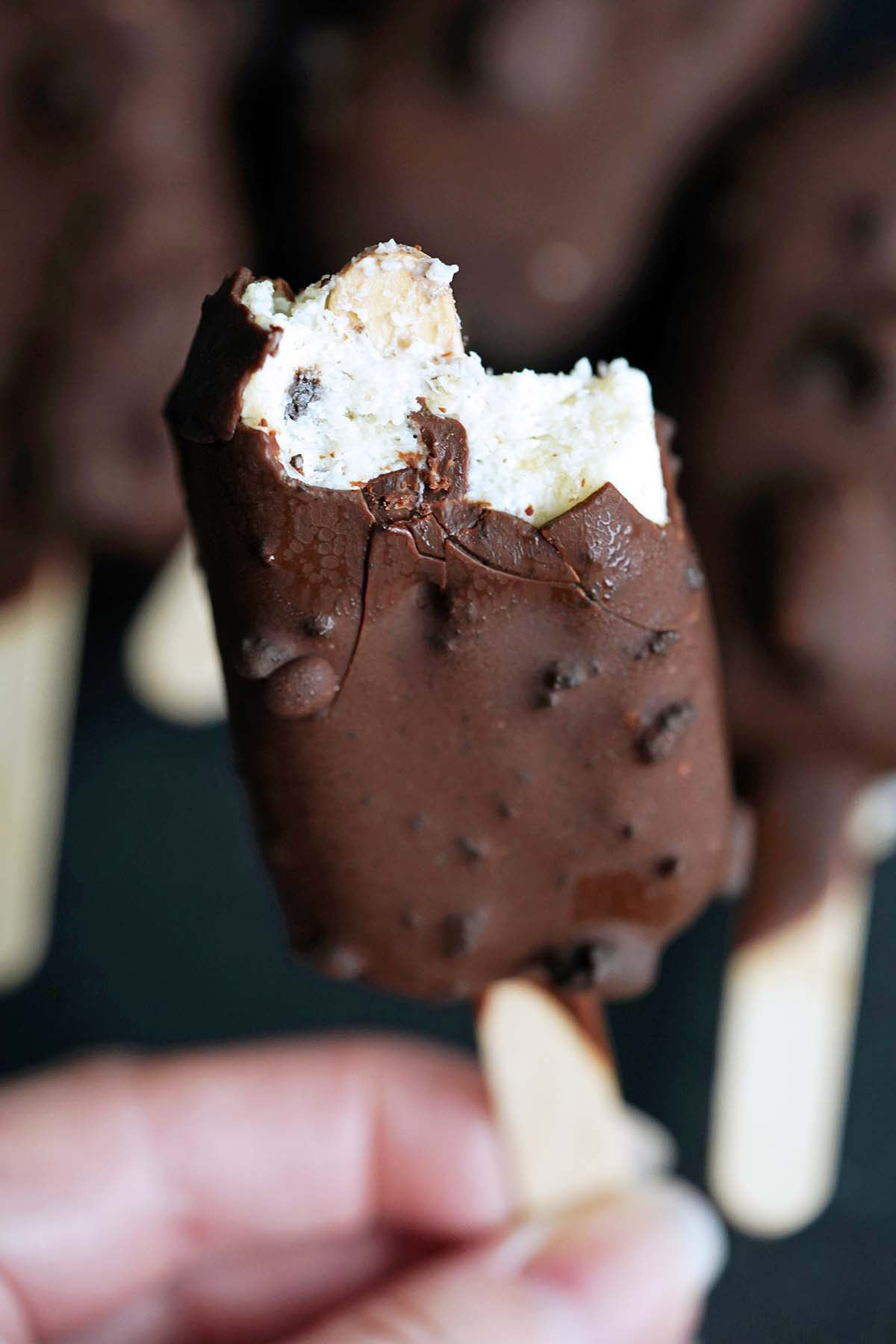 hand holding cookies and cream ice cream bar with bite to show creamy texture inside