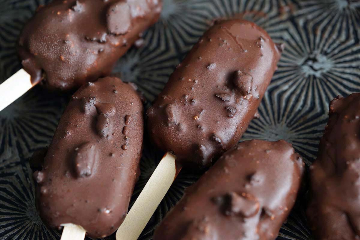 homemade healthy protein ice cream bars on vintage tray with chocolate magic shell coating
