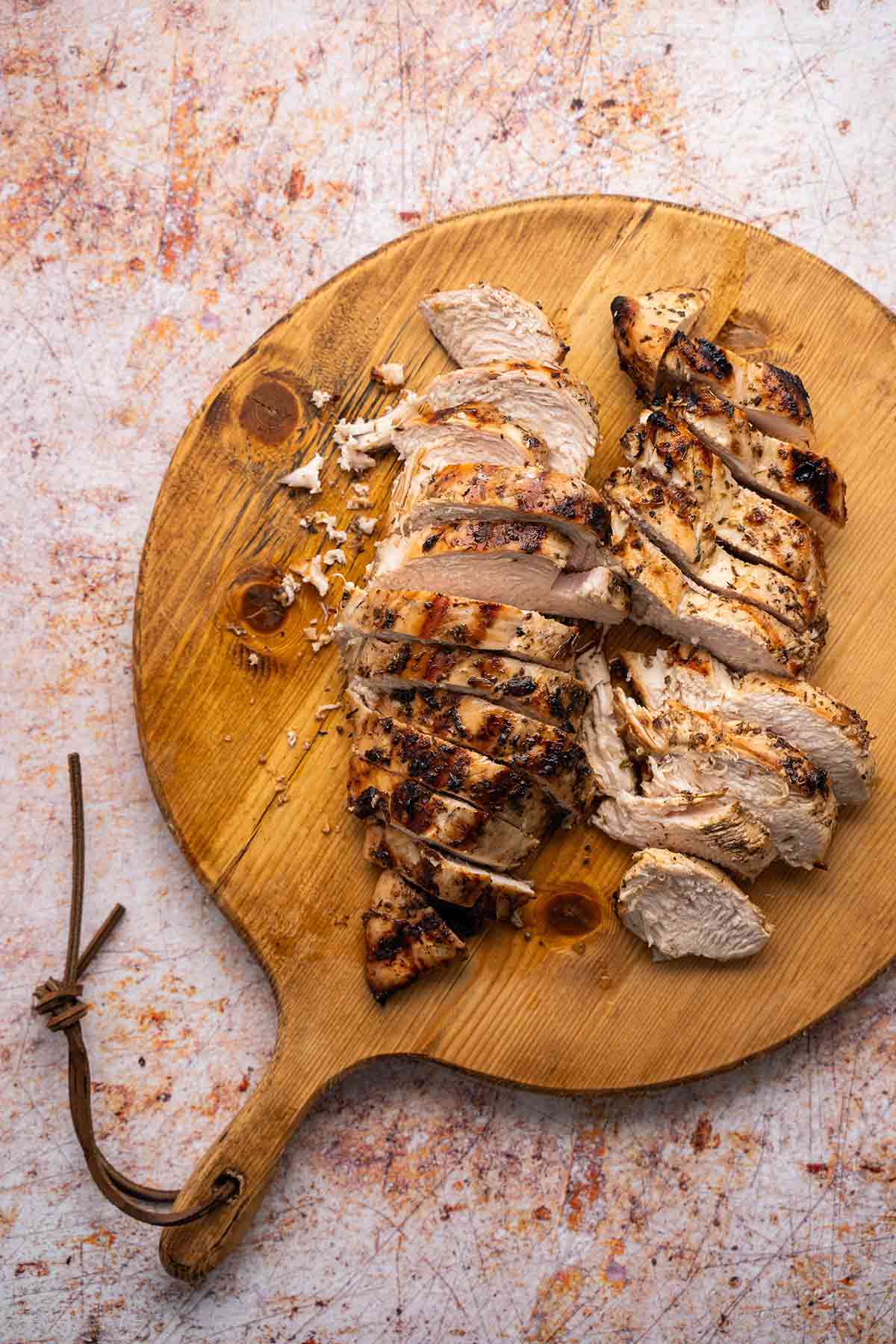 sliced grilled chicken on cutting board