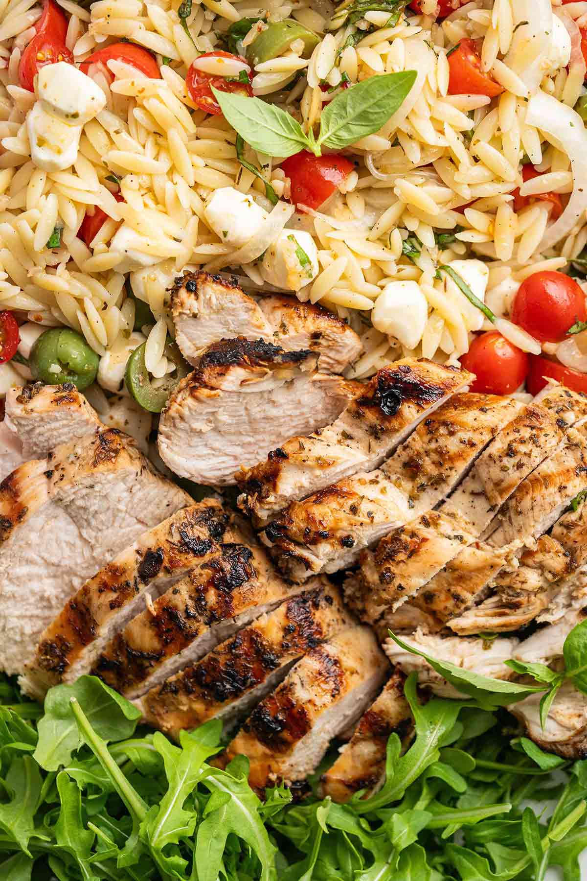 top view of Italian grilled chicken with orzo pasta salad and arugula
