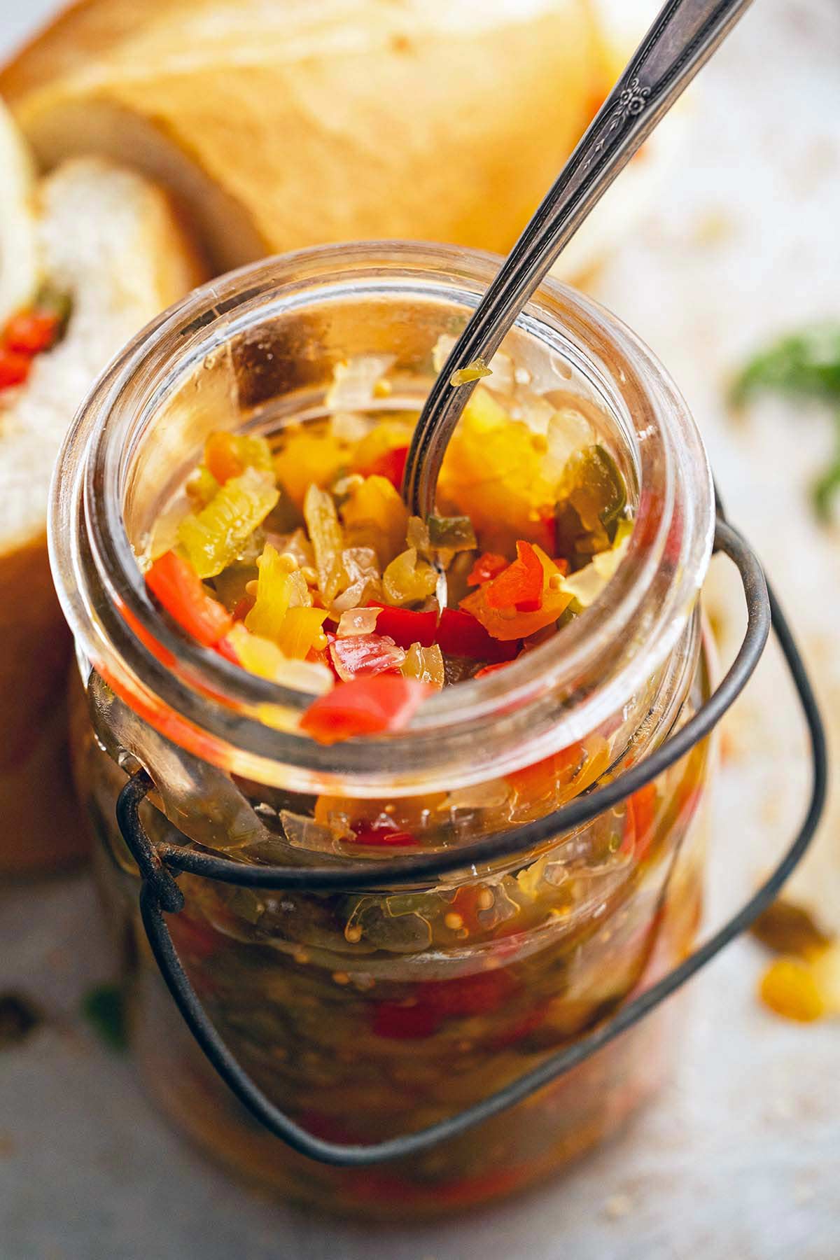 homemade pepper relish in vintage glass jar with sandwiches in background