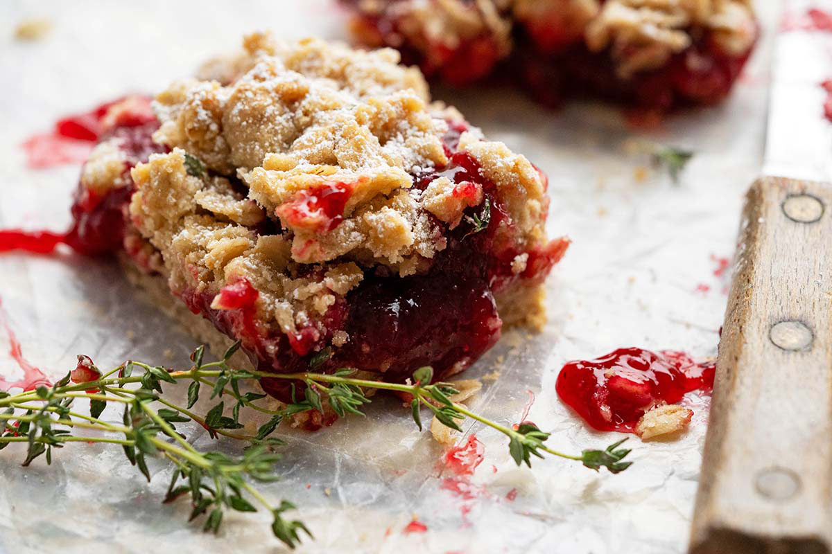 jammy gooey plum bars on parchment paper with fresh thyme