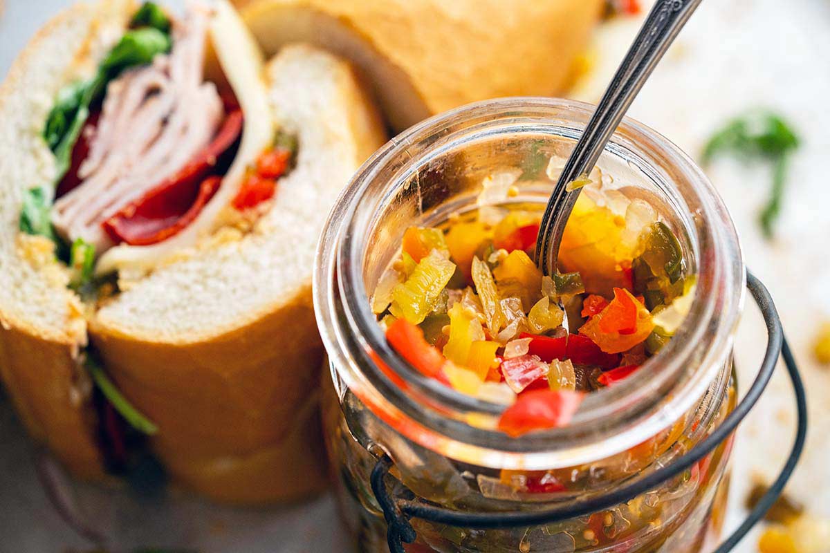 jar of homemade pepper relish next to Italian hoagie sandwich