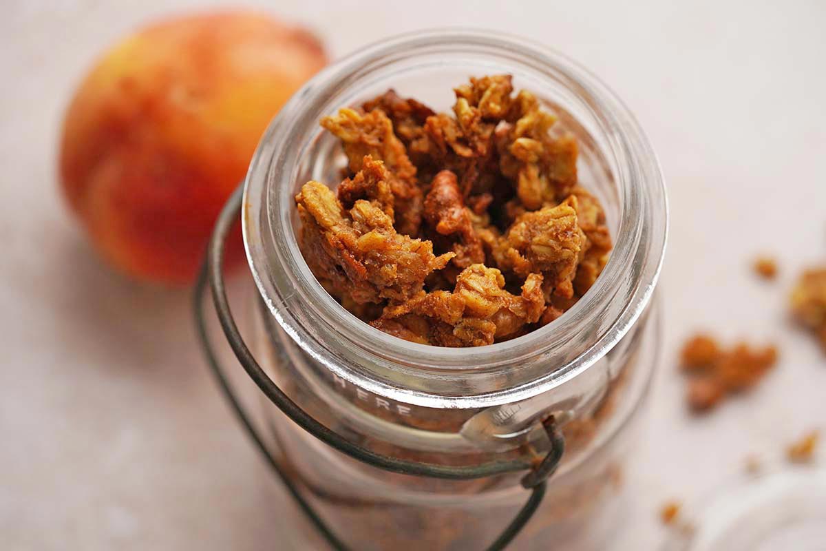 vintage glass jar of homemade granola with fresh peach