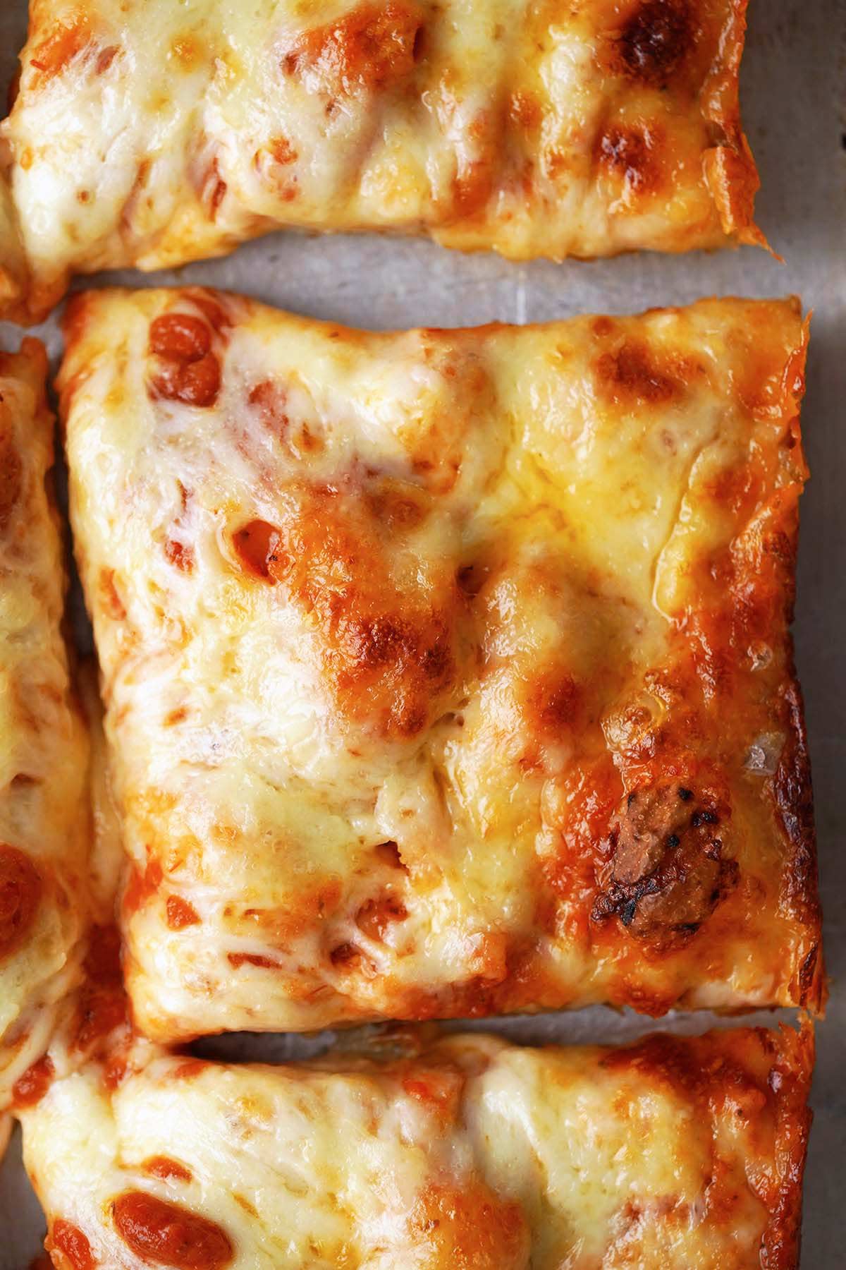 deep dish square pieces of pizza on baking tray