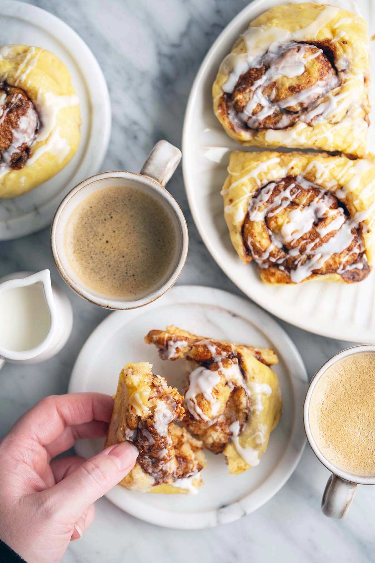 hand picking up soft chewy low calorie high protein cinnamon roll from marble plate