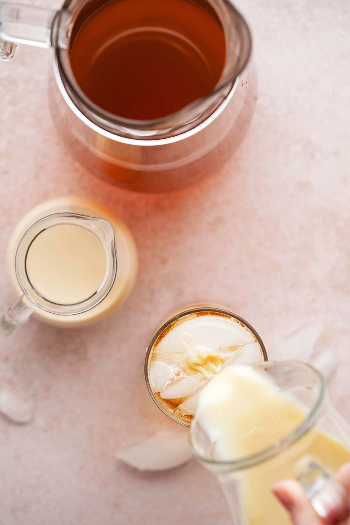 pouring sweetened condensed milk into glass of Thai iced tea