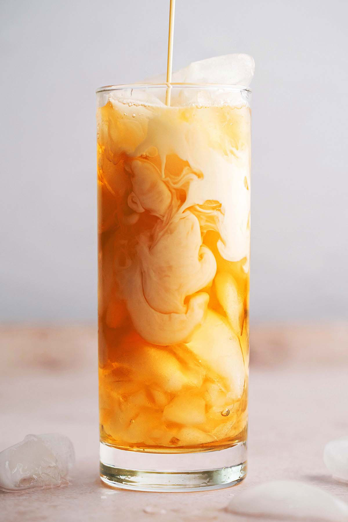pouring sweetened condensed milk into Thai iced tea