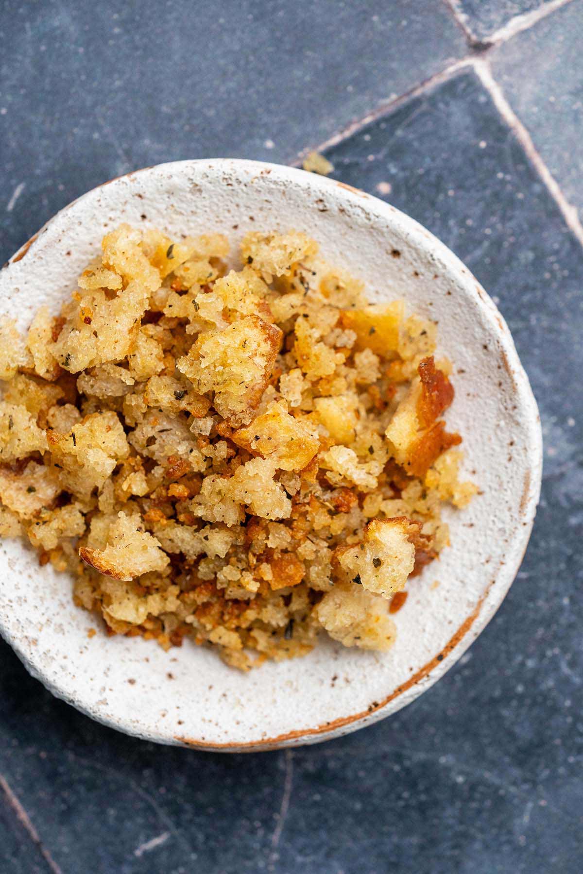 top view of seasoned toasted sourdough breadcrumbs on white stoneware plate