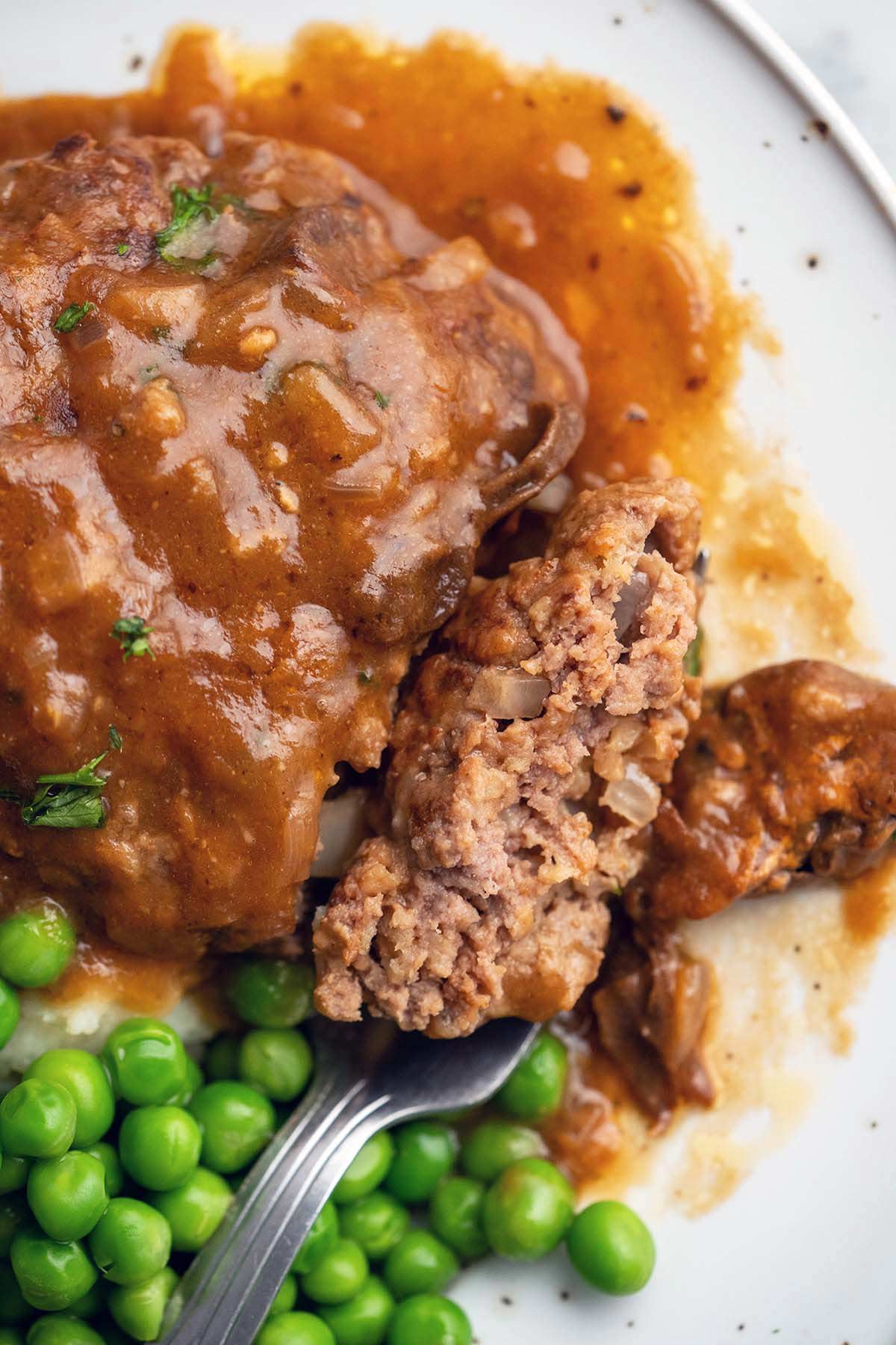 close up of homemade Salisbury steak with bite to show moist tender meat texture