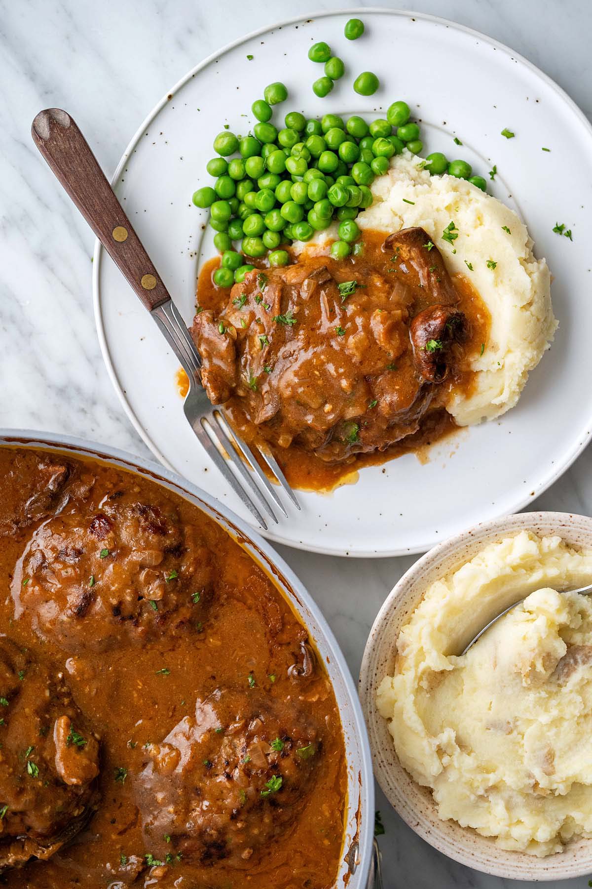 overhead view of old fashioned Salisbury steak meal with mashed potatoes and green peas