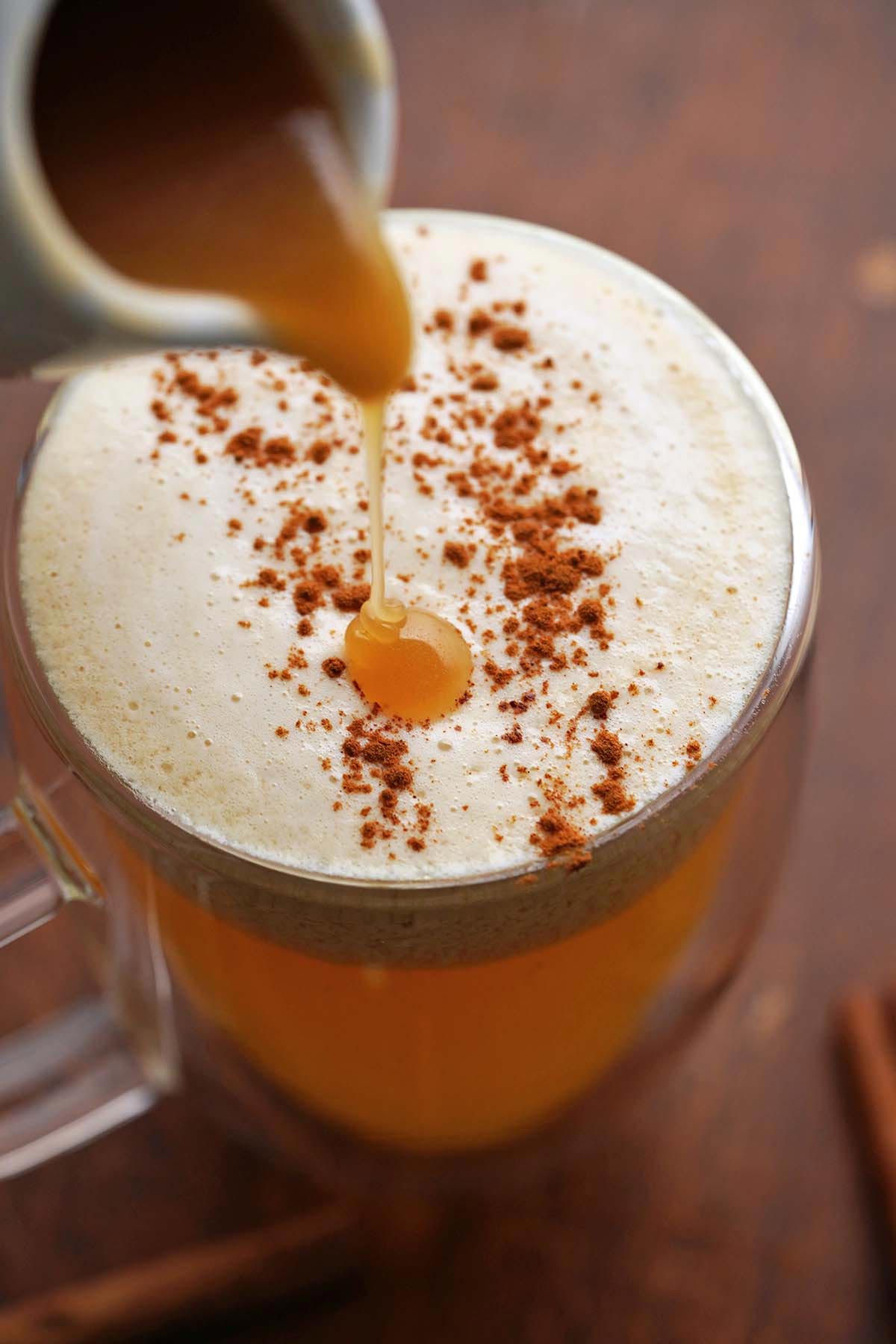 pouring homemade apple cider caramel syrup on hot spiced cider