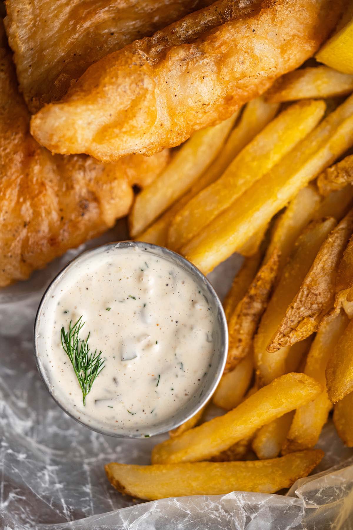 top view of fried fish and potatoes with cup of tartar sauce