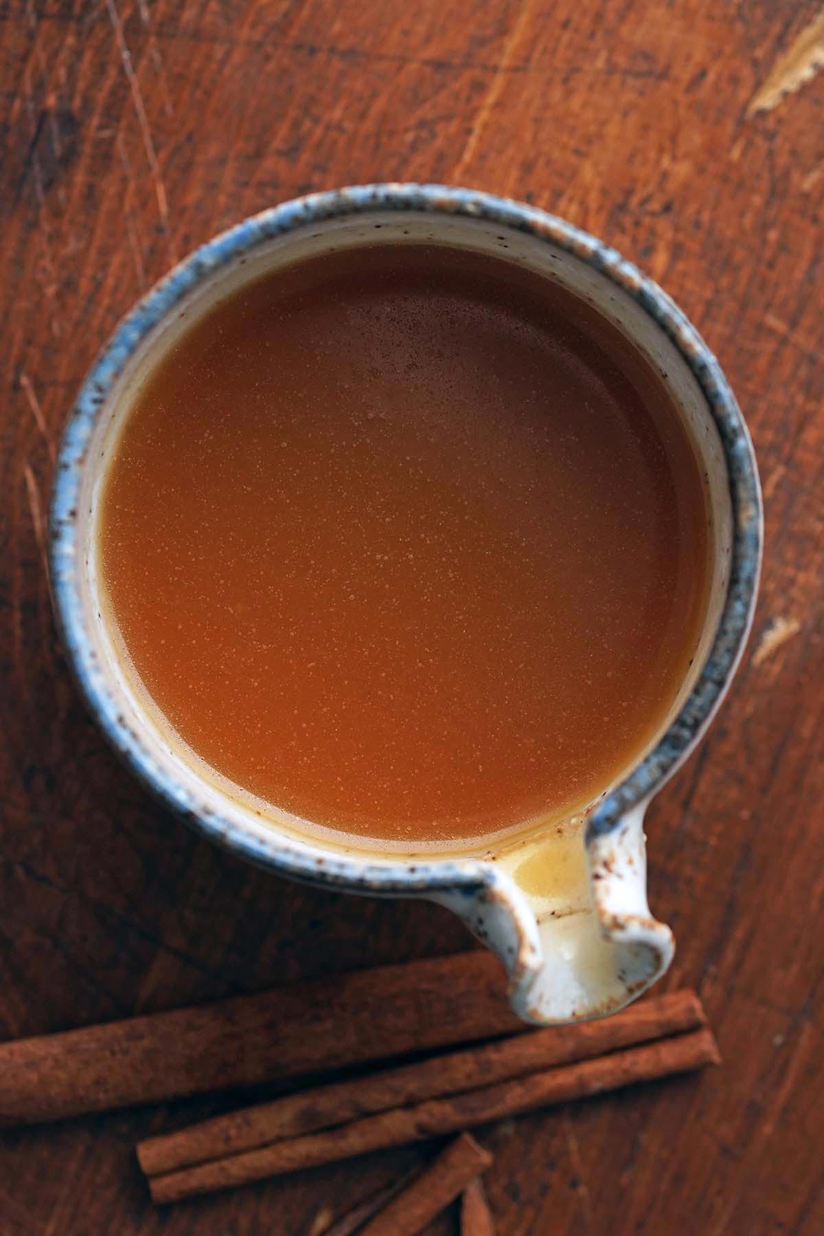 top view of small stoneware pitcher with apple cider caramel sauce on wooden table