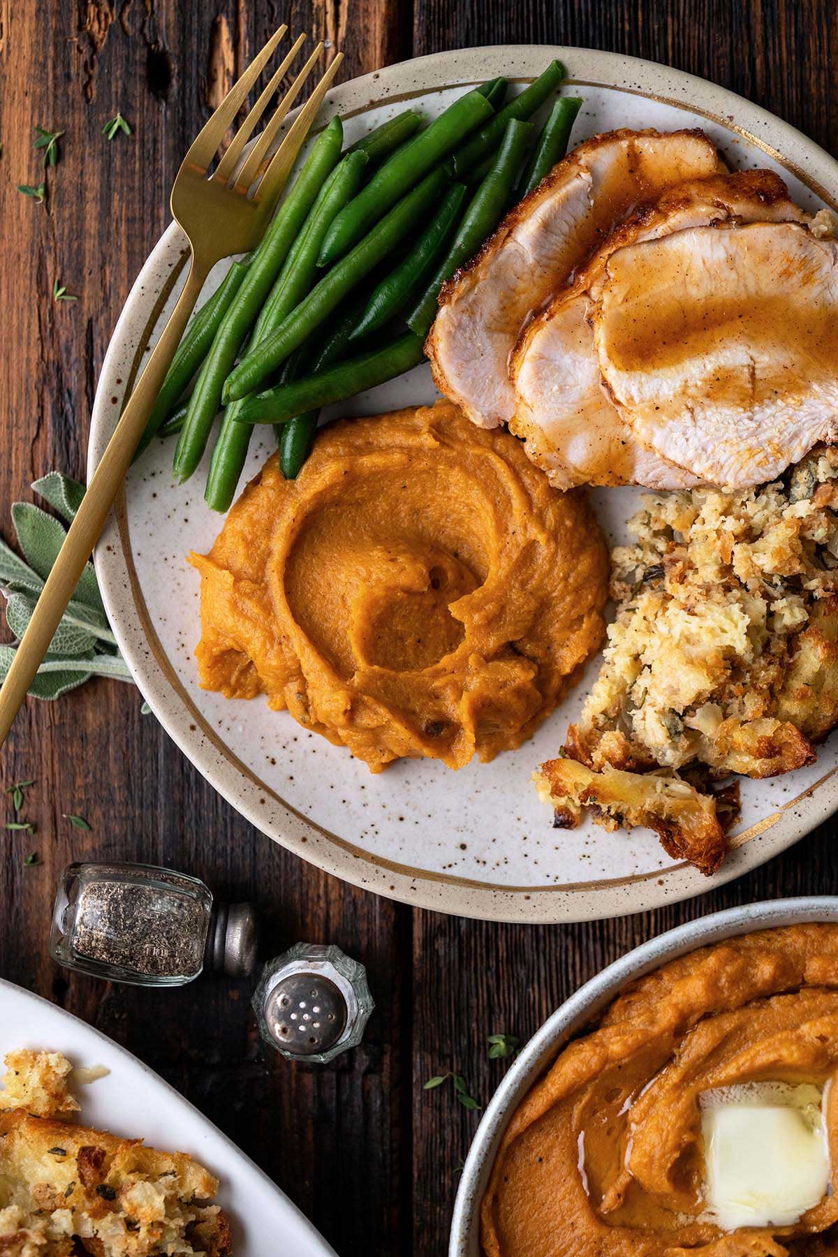serving plate of thanksgiving turkey dinner with stuffing sweet potatoes and green beans