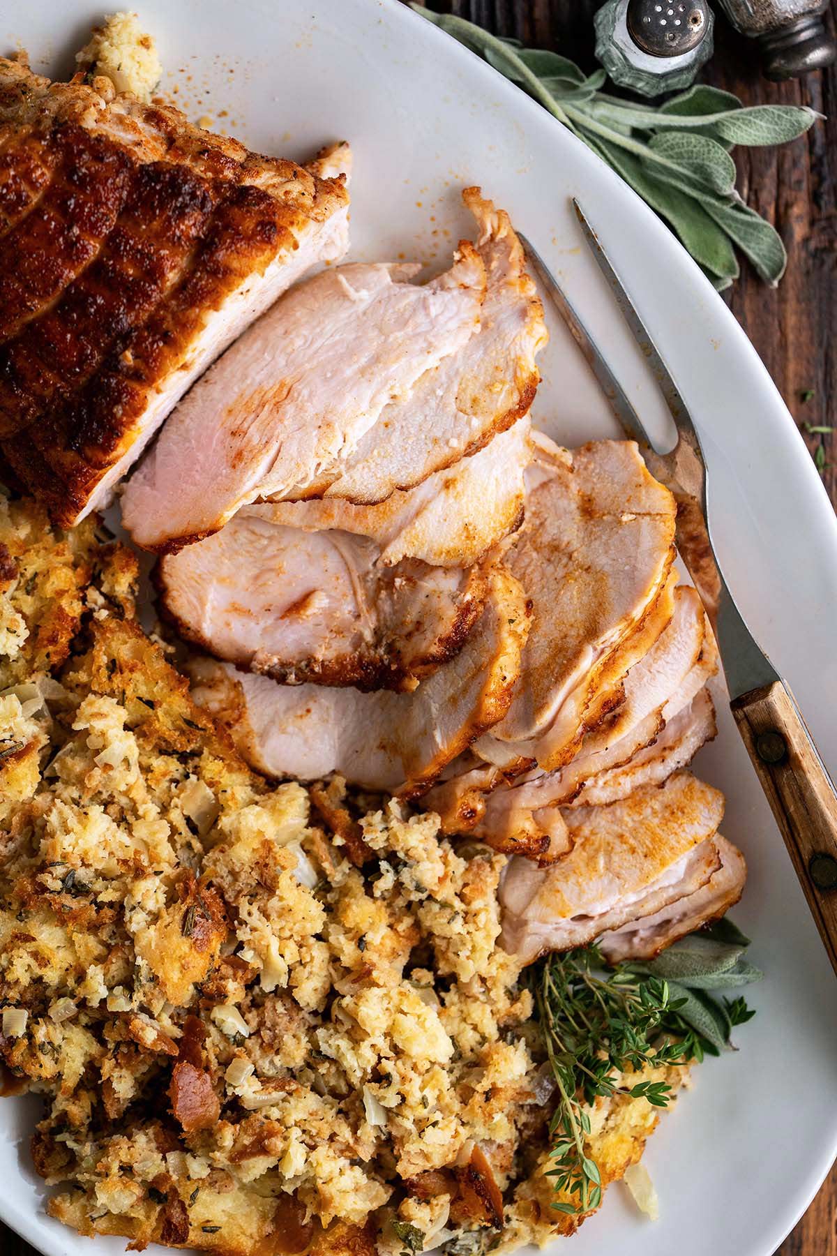 turkey and stuffing on white serving platter on rustic wooden table