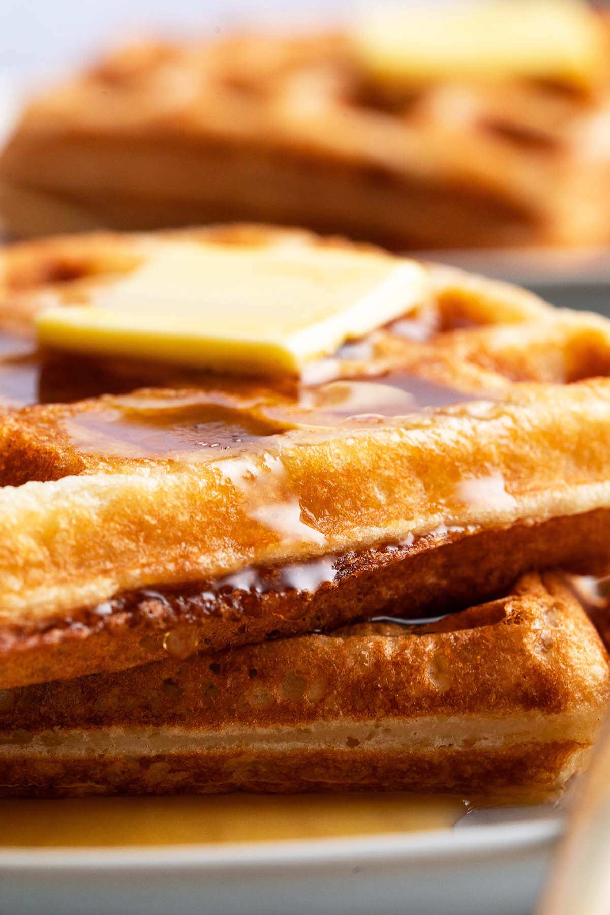 close up stack of crispy sourdough discard waffles topped with butter and maple syrup