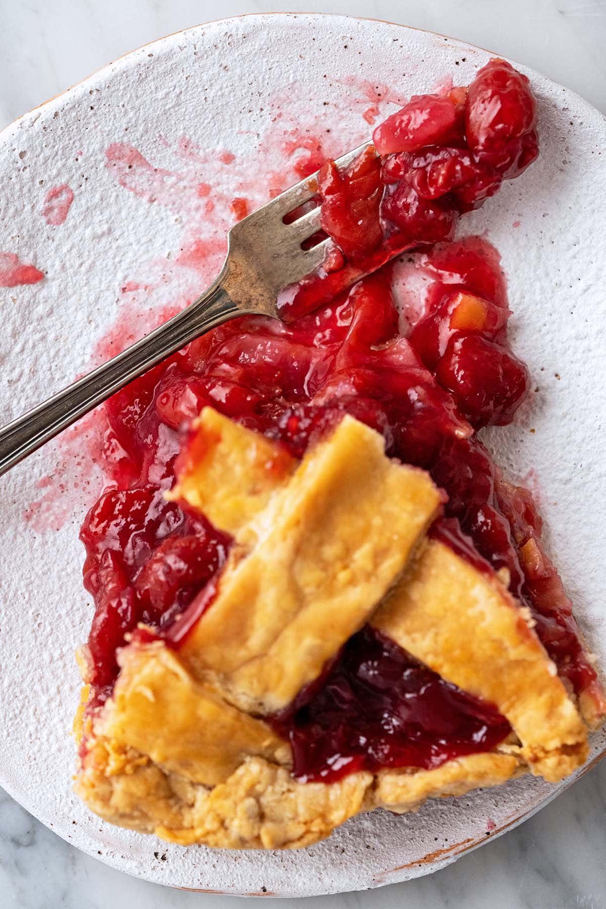 close up top view of slice of sour cherry pie with flaky butter crust