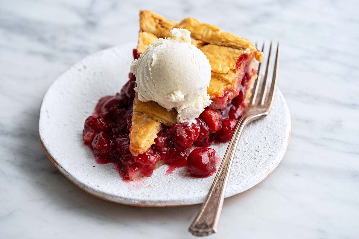 slice of cherry pie made with frozen cherries served a la mode with a scoop of vanilla ice cream