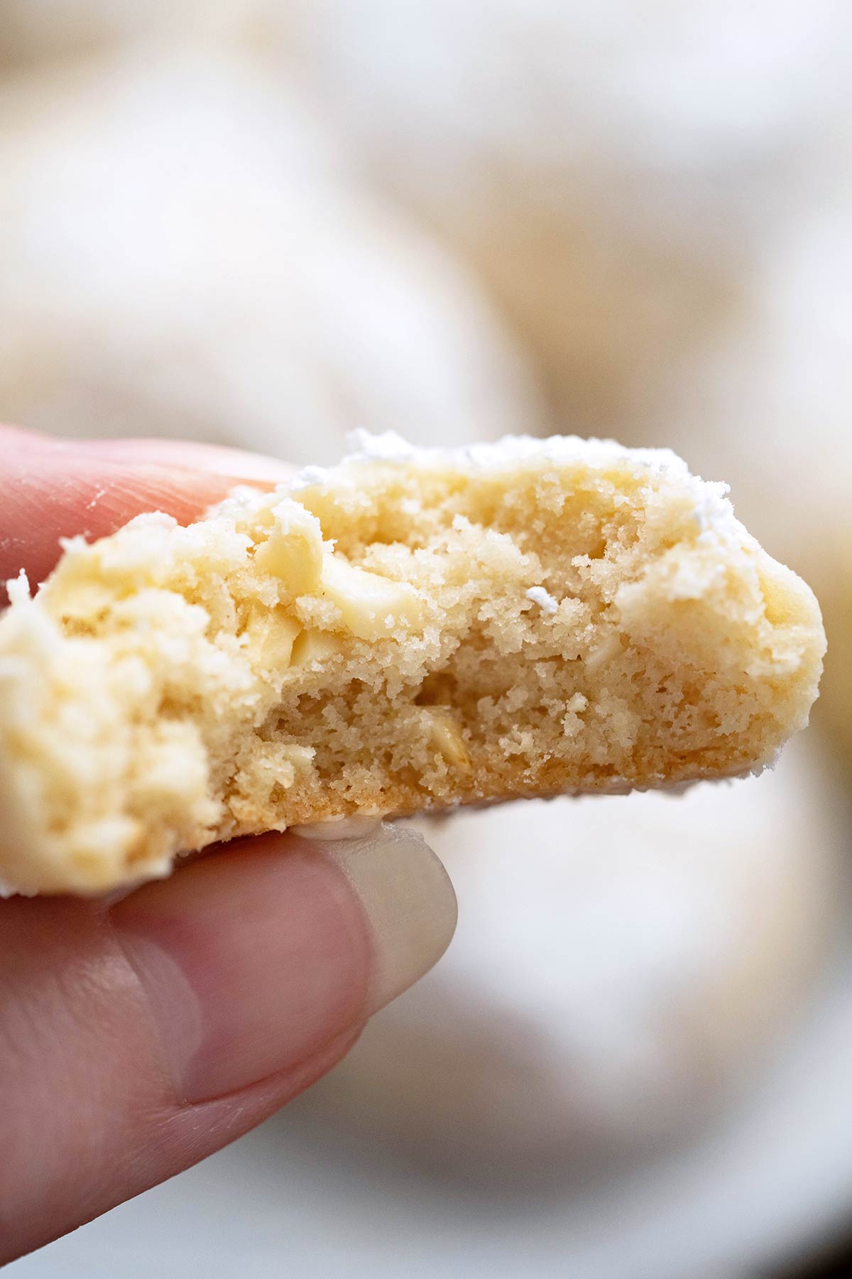 close up of hand holding half-eaten cashew cookies to show crisp delicate meltaway texture