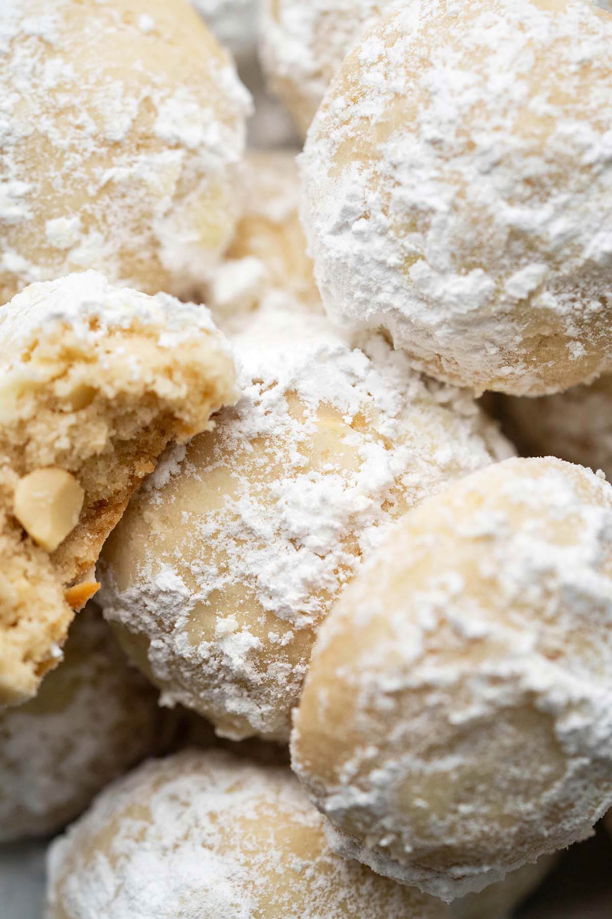 close up top view of stacked cashew cookies with bite out of one to show crisp light texture
