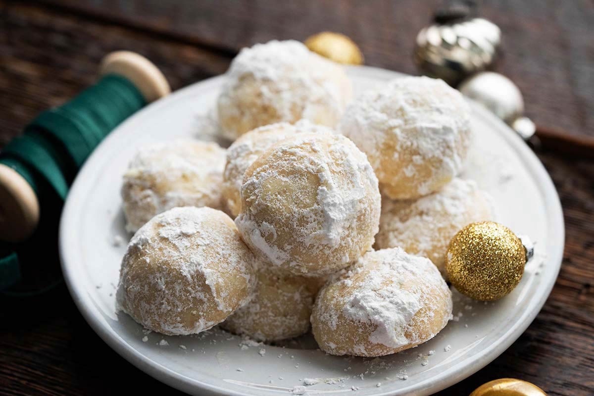 plate of holiday beltway cookies next to Christmas ribbon and ornaments on dark wooden table