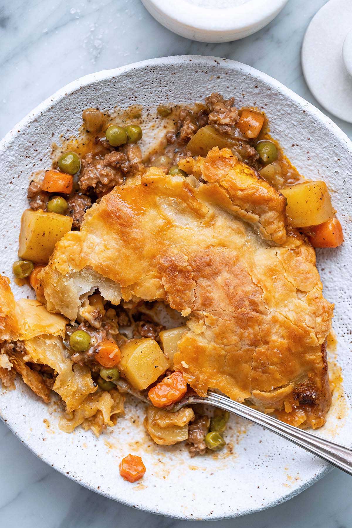 close up top view of easy meat pie with flaky crust in stoneware bowl