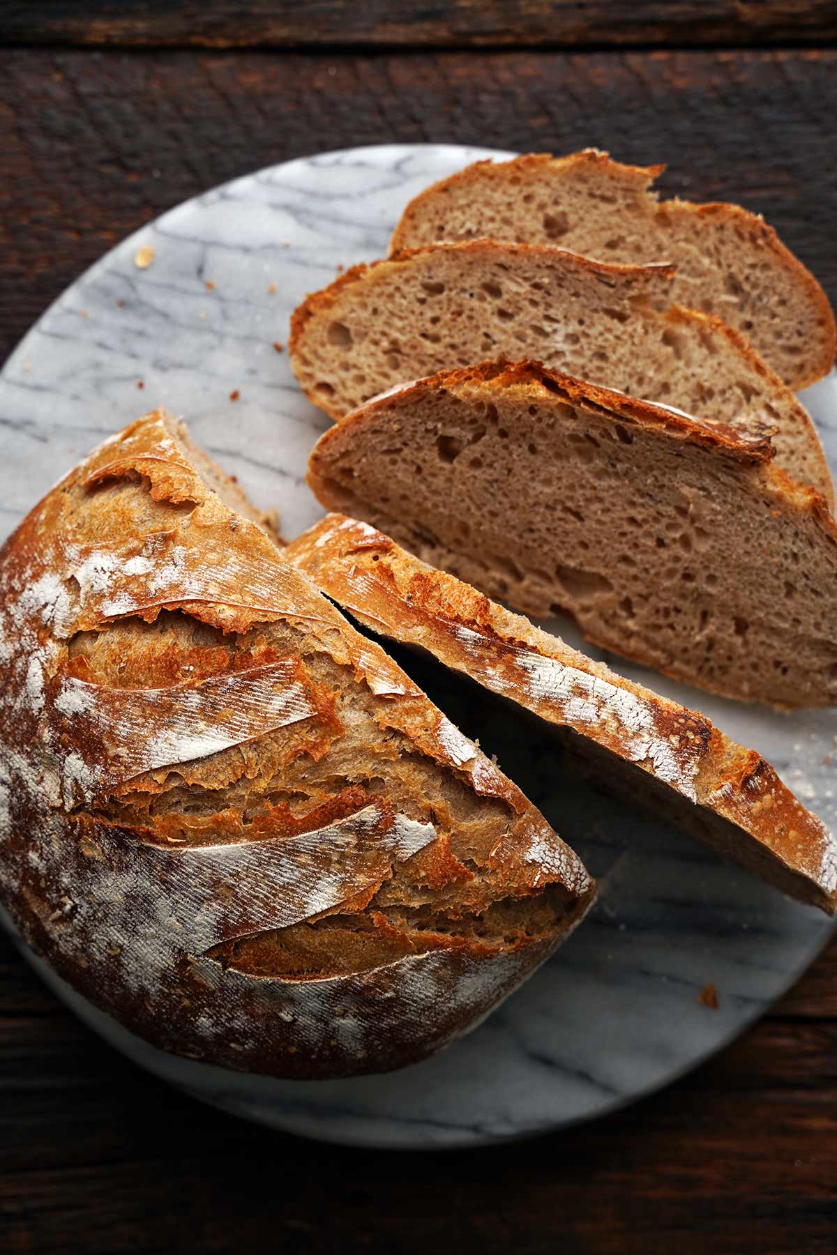 top view of crusty seeded rye sourdough sliced on marble cutting board
