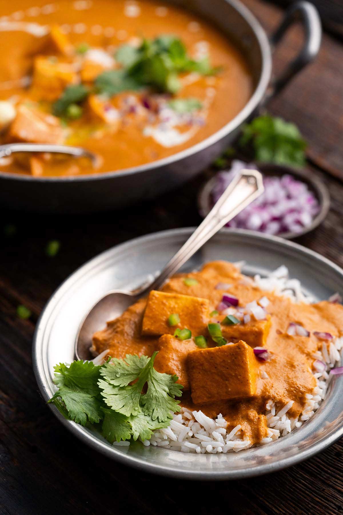 front view of dish of Indian butter paneer on top of basmati rice with cilantro