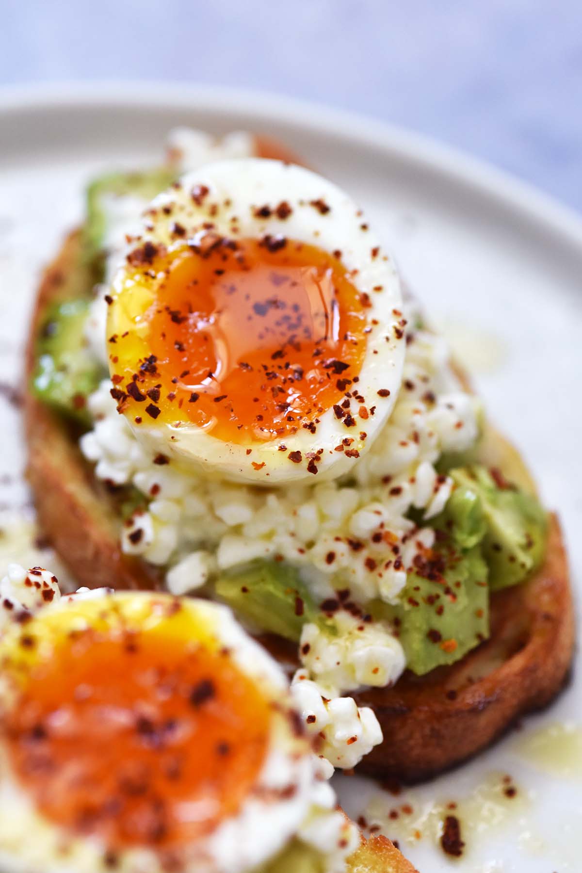 close up of gorgeous runny soft boiled egg yolk on avocado toast with Aleppo pepper and honey