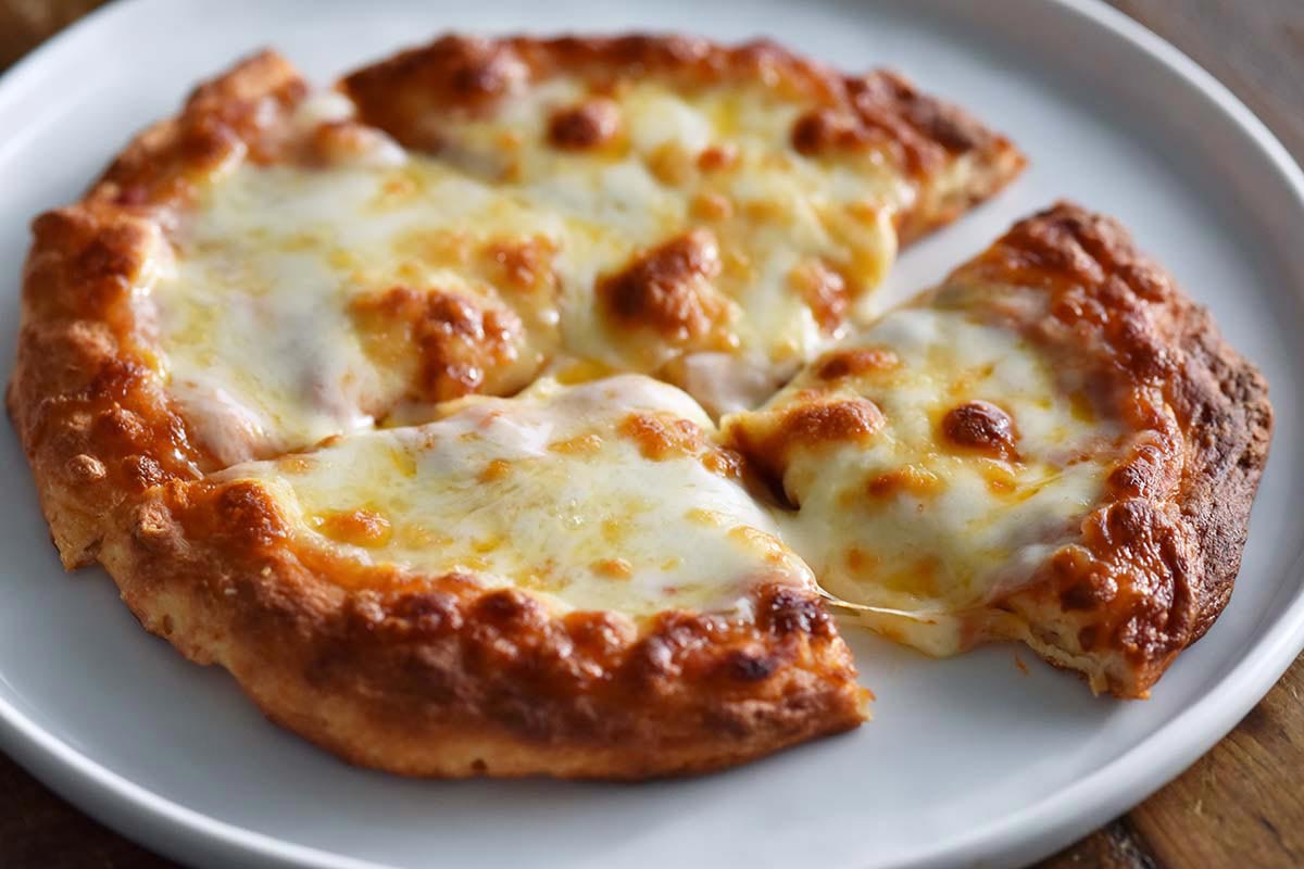 individual pizza made with 2 ingredient high protein greek yogurt dough on white plate