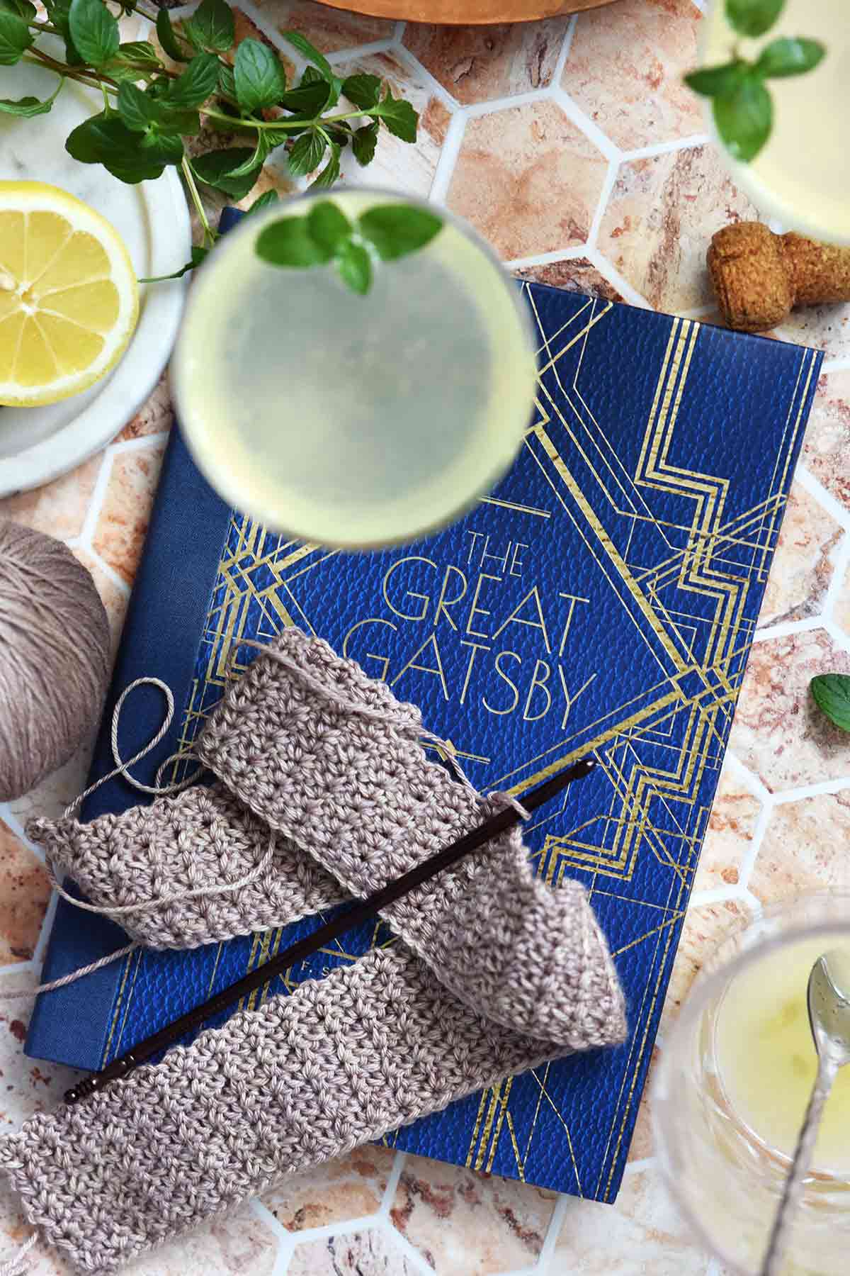 summer cocktail with reading material and crochet project on marble