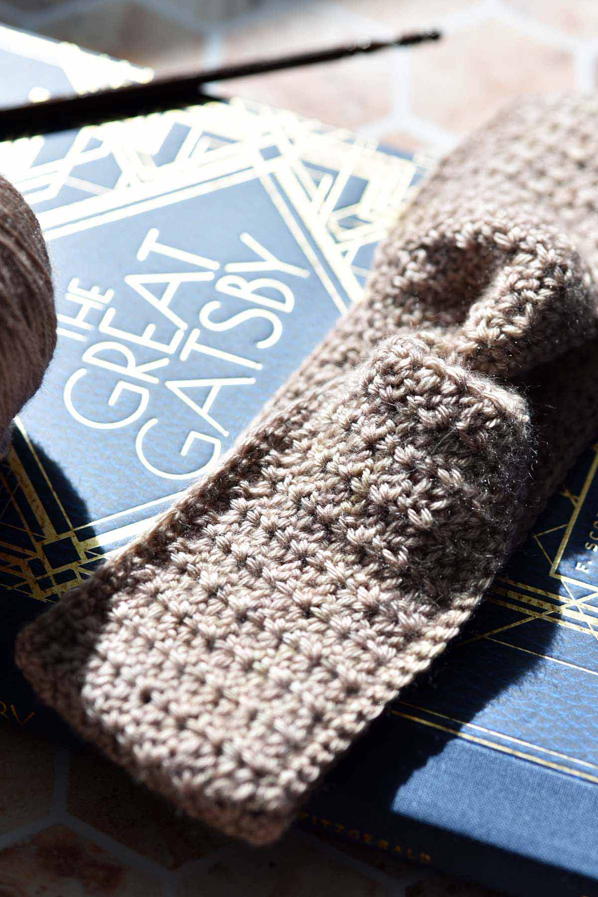 twisted crochet headband with fingering yarn and crochet hook on the great gatsby book
