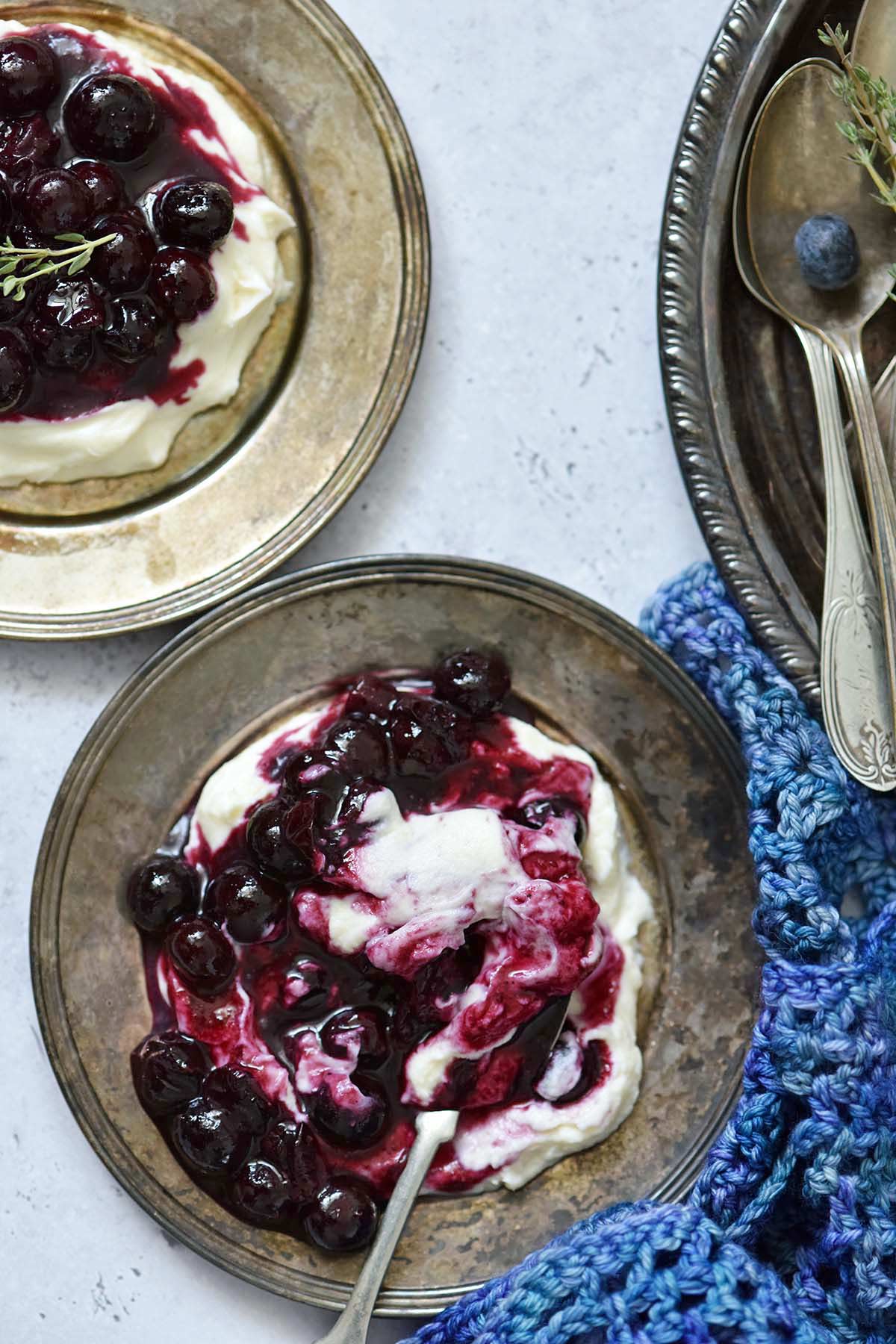 creamy whipped mascarpone cheese with roasted blueberries on silver plates