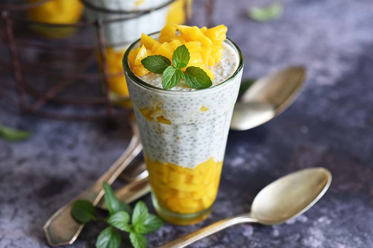 mango coconut chia seed pudding in vintage Indian glass with metal holder in background