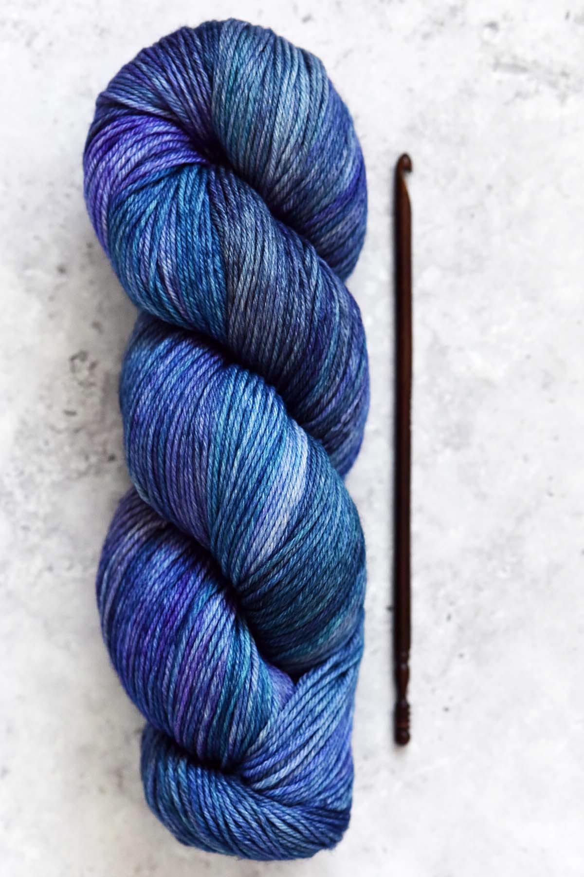 skein of Malabrigo Arroyo azaleas dk weight yarn with wooden crochet hook