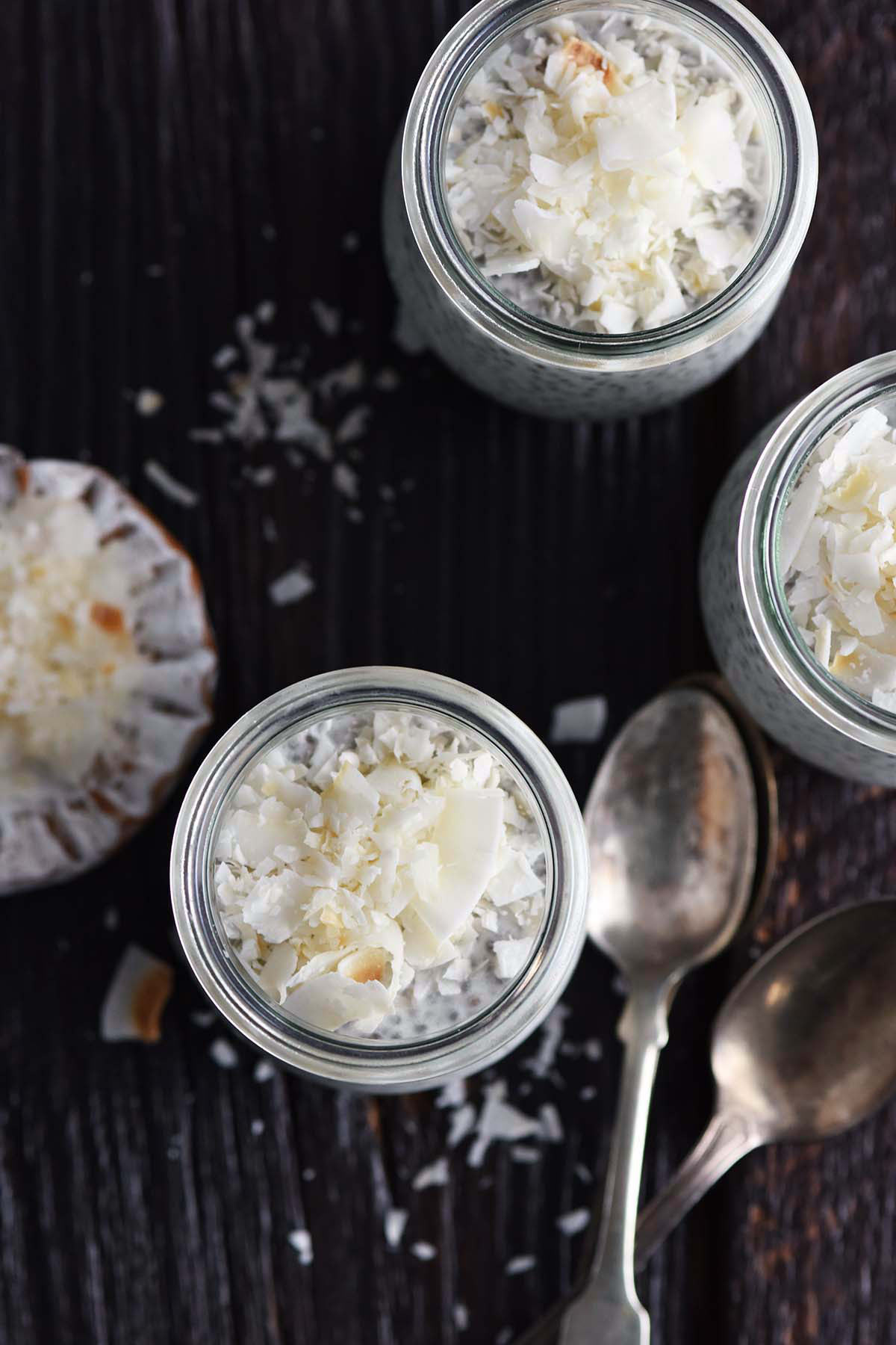 top view of coconut milk chia seed pudding with toasted coconut flakes garnish on rustic dark wooden table