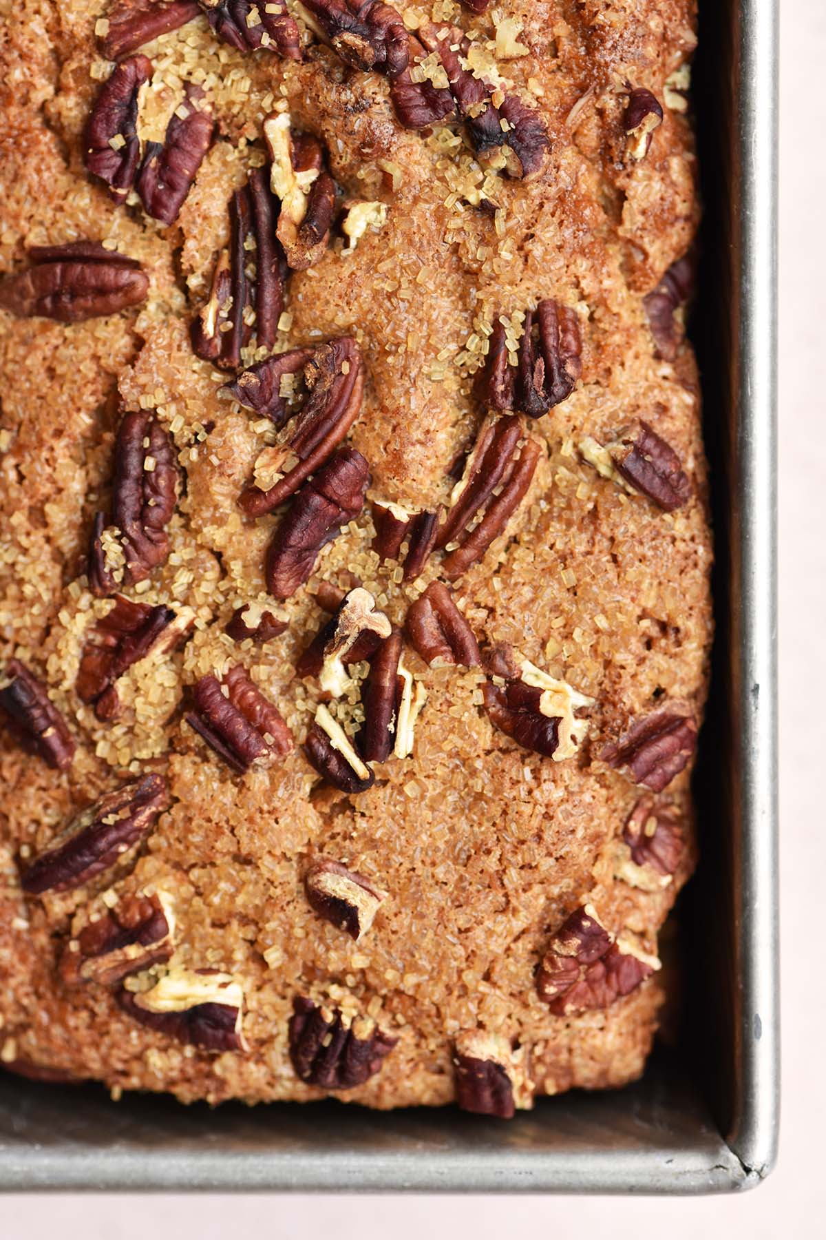 close up top view of peach quick bread made with sourdough starter topped with pecans and raw sugar