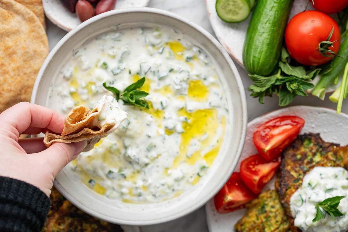dipping arabic bread into cucumber yogurt sauce