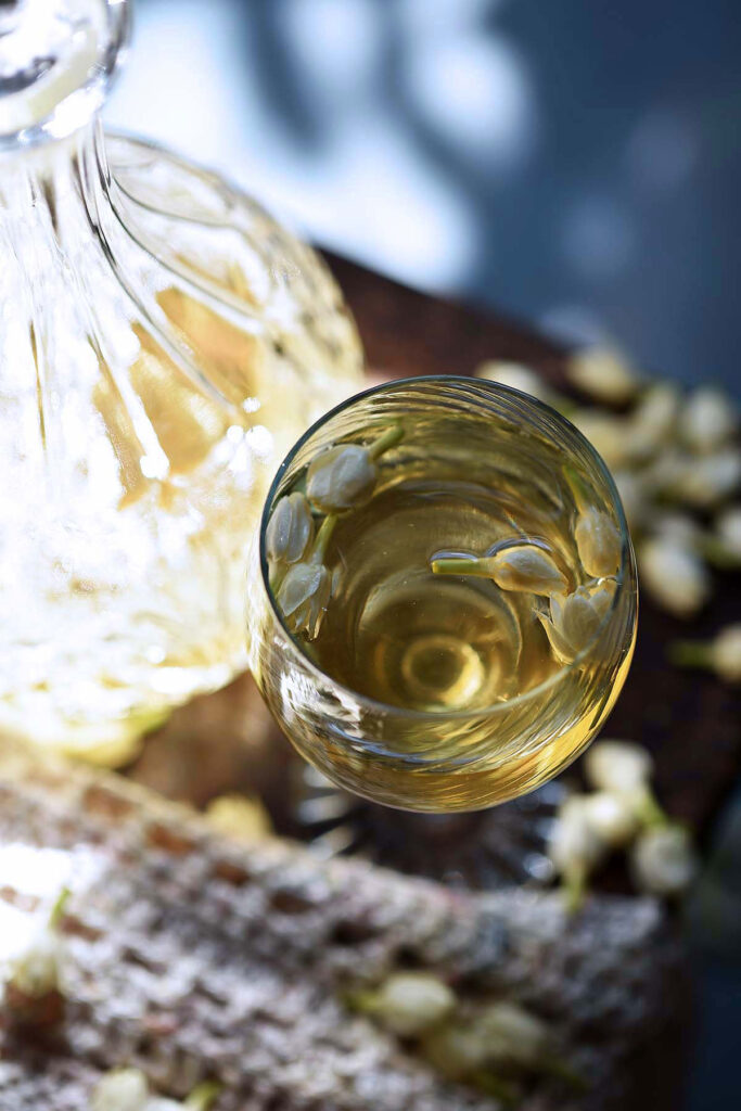 elven mead in glass next to sunlit glowing decanter