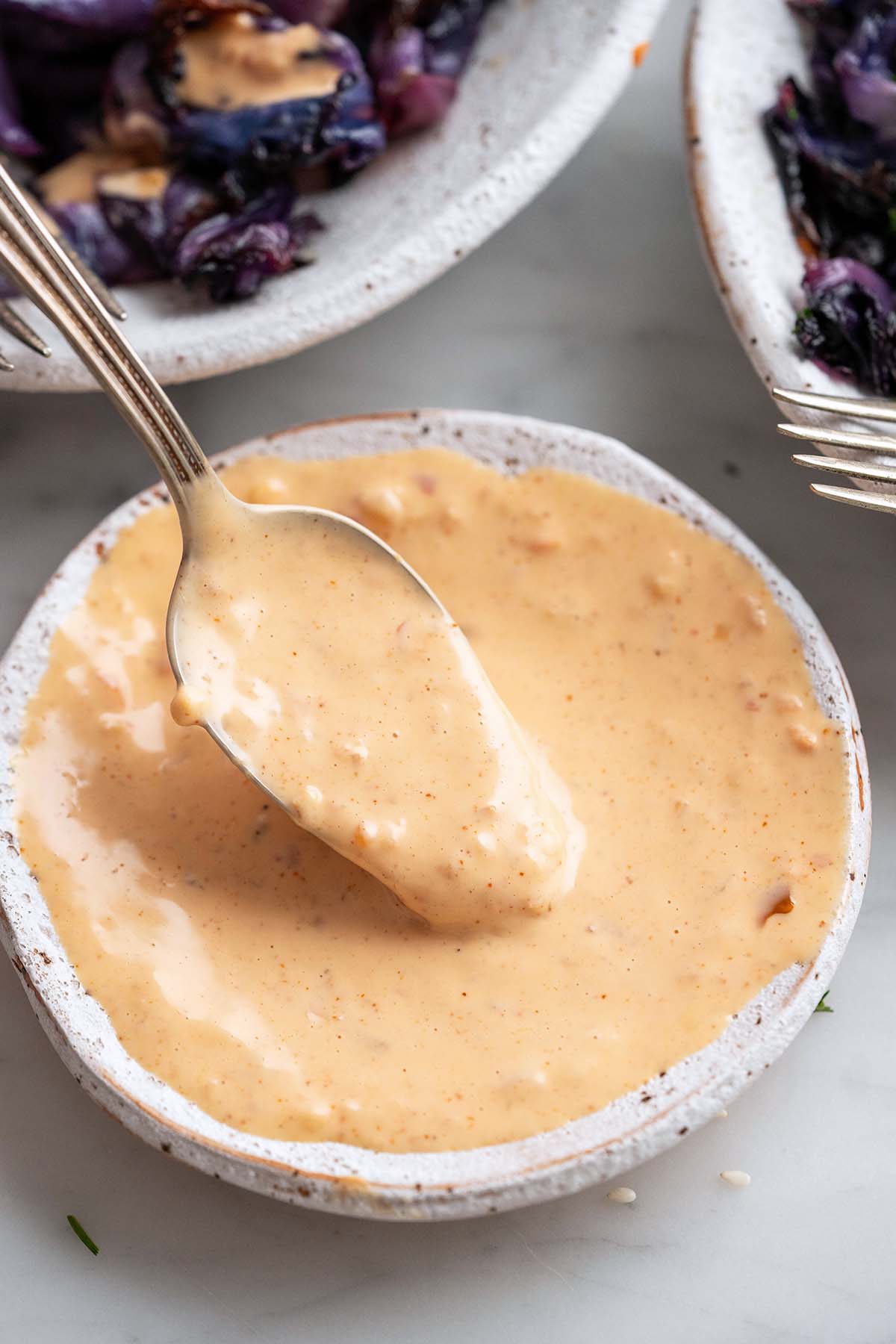 spoon drizzling homemade spicy garlic mayo sauce